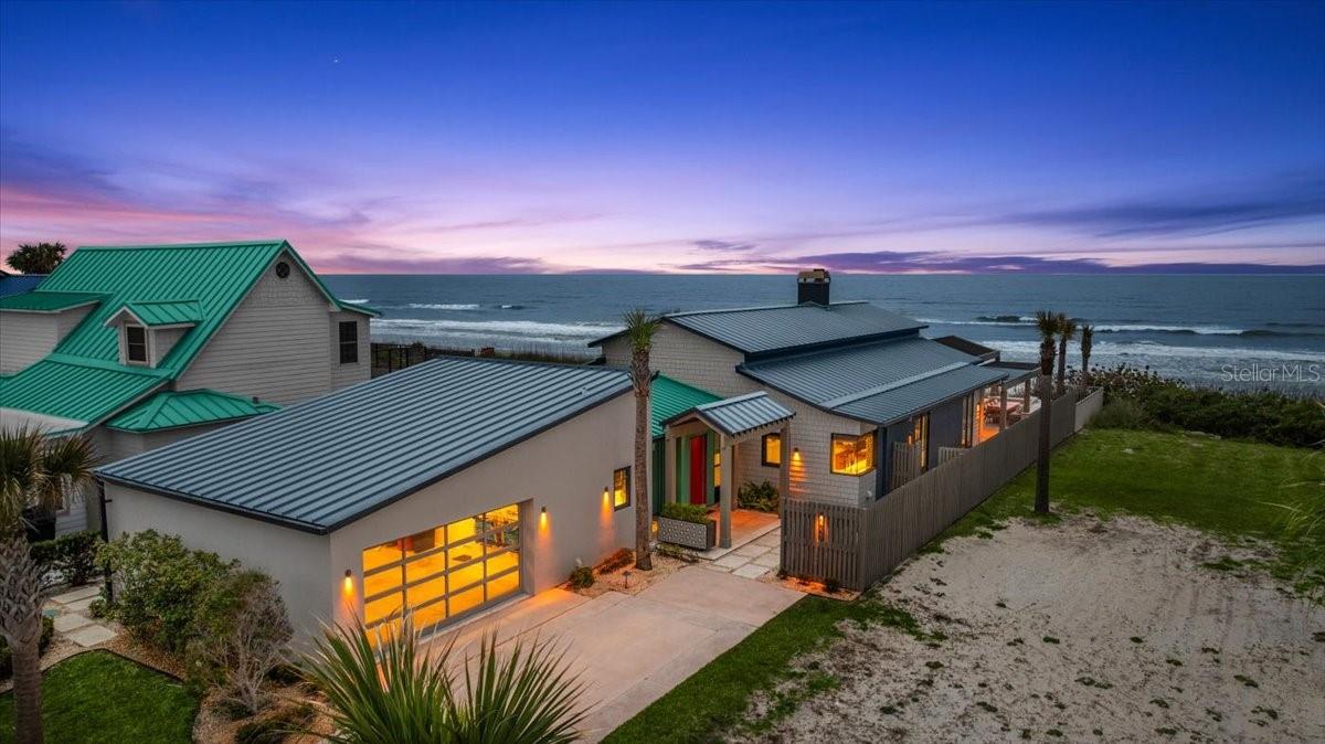 Sold note: property was sold with previously unlisted neighboring vacant lot (50x160 approx). Prepare to be amazed as you step into this one-of-a-kind, newly finished Oceanfront home in the heart of New Smyrna Beach. Classic contemporary design meets coastal elegance, from state-of-the-art materials, construction and craftsman used; no expense was spared for long lasting durability, design and comfort. Central location offers easy access from the South Causeway. The proximity to the Publix Shopping Center, a variety of stores and restaurants allows for a walking friendly community. Property falls within the coveted short term rental district. As you approach the entryway, you will notice a combination of design and textures that welcome you to this architectural masterpiece. Inside, pops of color, designer wallpaper, and exceptional fixtures, to name a few. A spacious entry hallway provides access to two guest rooms with an adjoining Jack and Jill bathroom and a top of the line laundry room. Living and kitchen area greet you with vaulted ceilings adorned with tongue and groove pine and dramatic beams. The open kitchen features a beverage center island with Sub-Zero custom panel refrigerator and freezer drawers, cherry wood center island with heat resistant Dekton top, Dacor drop in natural gas cooktop with GE telescopic downdraft venting system, and a generous overhang with seating for three. Other kitchen highlights include GE Monogram wall oven, Sharp microwave drawer, recessed cabinet and open shelving lighting with dimmers, Bosch custom panel dishwasher and GE Monogram counter depth refrigerator with ice drawer. Kitchen entertaining space blends seamlessly into the living and garden room, with beautiful views of the pool deck and ocean. Half bath is located off side entry door next to the outdoor shower, allowing for low traffic through the home from the pool deck. Hunter Douglas remote controlled shades make it a breeze to adjust lighting in the living area, kitchen, and primary bedroom. Plenty of seating and dining space, cozy gas fireplace lounge area, and low maintenance landscaping with custom made planters, turtle friendly lighting, and irrigation system. Travertine pool deck features a heated salt water pool, gas fireplace, and beautiful pergola constructed with powder coated aluminum and Ipe Brazilian wood. Home is equipped with impact rated windows and doors. Interior design by Jan Burket of Jan Burket Interior Design, Kansas City; exterior design by Kristopher Dabner of The Greensman, Kansas City; architectural design by Brent Kandal, New Smyrna Beach; General Contracting by Don Smith of DPS, Lake Mary. This property comes fully furnished and is turnkey with top of the line kitchen supplies, linens, beach gear, gas grill, and more, just pack your bags. This is a must see!!