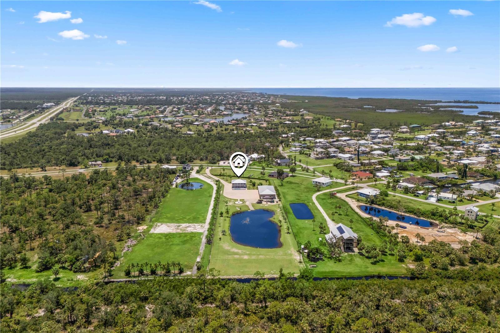 A STUNNING HOME ON FOUR ACRES WITH PRIVATE LAKE AND A 5,000 Sq foot garage - it will easily hold 18 plus cars with plenty of additional room! This property is meticulous and unrivaled with possibilities! GORGEOUS renovated home in the peaceful boating community of Pirate Harbor in Punta Gorda, Florida set on its own private gated and fenced lot. This elevated, move-in-ready residence features 2 bedrooms + den, 3 full baths, and 1 half bath, with f thoughtfully redesigned space. Every inch has been updated to provide modern comfort, coastal charm, and functional design in a prime canal-side setting. The interior boasts an open-concept layout with a fully remodeled kitchen featuring Corian countertops, stainless steel appliances, and contemporary cabinetry. The main living spaces are finished with luxury vinyl plank flooring, combining timeless style with everyday durability. Lots of natural light fills the home, creating a bright and welcoming atmosphere. Both bedrooms are spacious and well-appointed, while the bathrooms are updated with high-end materials and clean, modern styling. In the downstairs garage there is a versatile space currently used as an office/den that can easily be converted into a third bedroom, providing flexible living options. The garage also includes a half bath and is equipped with an easily installable flood protection barrier, offering added security and peace of mind during storm season. The property also features a massive, detached warehouse/garage capable of housing up to eighteen plus vehicles, with its own full bath, workshop space, and a matching flood barrier system—making both structures storm-prepared while still easily accessible for daily use. This setup is ideal for car collectors, hobbyists, or anyone needing serious storage and utility space.. Additional bonus - dedicated area for RV parking, complete with water and sewer connections to support your recreational lifestyle. Step into the fully fenced backyard, your own private oasis completes with a sparkling pool and custom outdoor kitchen—perfect for entertaining guests, relaxing with family, or soaking up the Florida sun in privacy. Additional highlights include a metal roof for long-term durability and low maintenance, as well as southwest-facing front exposure, which fills the home with warm natural light and stunning sunset views. Located just minutes from open water via Pirate Harbor’s deep-water canal system, in a neighborhood POA of only $150 a year which includes boat access, this home is a true dream, with quick access to Charlotte Harbor and the Gulf of Mexico. You're also conveniently close to downtown Punta Gorda, I-75, waterfront dining, marinas, and Gulf Coast beaches. Whether you're seeking a full-time home, seasonal escape, or a versatile waterfront property with premium features and smart storm-ready enhancements, 24490 Yacht Club Blvd delivers exceptional quality, peace of mind, and the relaxed Florida lifestyle—all in one of Southwest Florida’s most desirable boating communities.