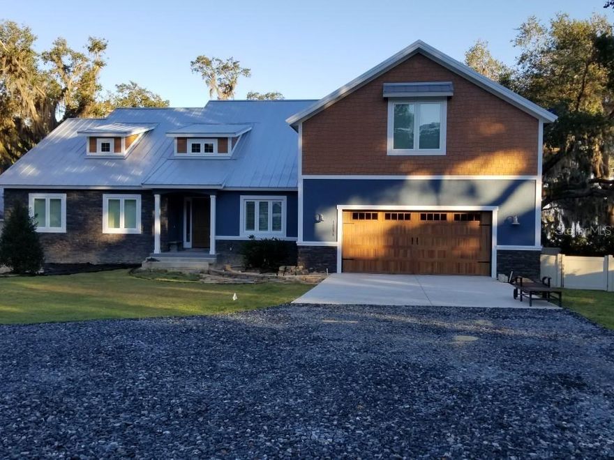 Under contract-accepting backup offers. Enjoy sunset views on Lake Weir from your porch.  This custom two story home was built by CENTER STATE CONSTRUCTION in 2017.  The home boasts 4739 square feet of living area and 6383 square feet of total square footage.  Home also has a detached garage/storage loft that is an additional 2936 of square feet. This was designed for an RV! This custom home has 5 bedrooms and 4 baths plus a huge bonus room.  Wide open floor plan with two story great room and a floor to ceiling fireplace.  Lots of custom wood working, hickory floors, large screened lanai with a balcony to drink coffee from in the mornings.  128 feet of lake frontage, private gate and fenced in property.