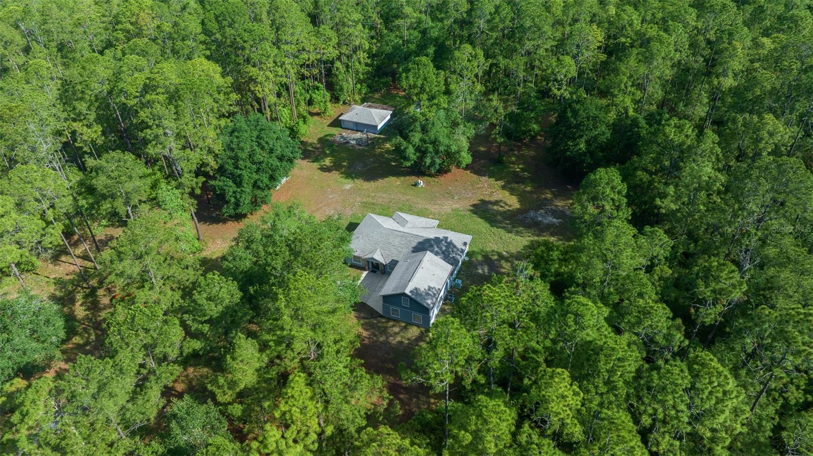 One or more photo(s) has been virtually staged. This isn’t just a house, it’s a homestead. Sitting on 20 pristine acres, this property comes with a brand-new roof and a HVAC system, giving you peace of mind for years to come. The 3,000 sq ft home was built with family and function in mind. You’ll find wide open spaces inside, including a 28x23 family room big enough for gatherings and includes a half bathroom, a central kitchen with a breakfast area that looks out over the wooded back yard, and a large dining area for special meals. The main living area's primary suite has a spacious bath, walk-in closet, and private door out to the screened lanai, just right for starting your morning with a cup of coffee and a view of the woods. Upstairs above the family room, there’s another full suite with full bathroom, perfect for extended family or guests who want their own space. Two more bedrooms and a full bathroom complete this home's floor-plan. Outside, a covered pavilion with power makes for easy cookouts and get-togethers. The detached 3-car garage (30x22) gives you room for trucks, tools, or toys, and the RV carport adds more storage options for a travel trailer or boat. The expansive backyard offers a blank canvas, ideal for designing the custom pool retreat you’ve always imagined. The land is zoned for Agriculture use and is a mix of open ground and woods, ready for trails, livestock, gardens, or even horses. With 20 acres, you’ve got options - keep it whole, or explore subdividing for additional homesites down the line. With its size, updates, and acreage, this property is priced well below similar estates in the area, making it not only a rare find, but a smart investment. All this, and you’re still within reach from the World Equestrian Center, with quick access to both I-75 and I-95.