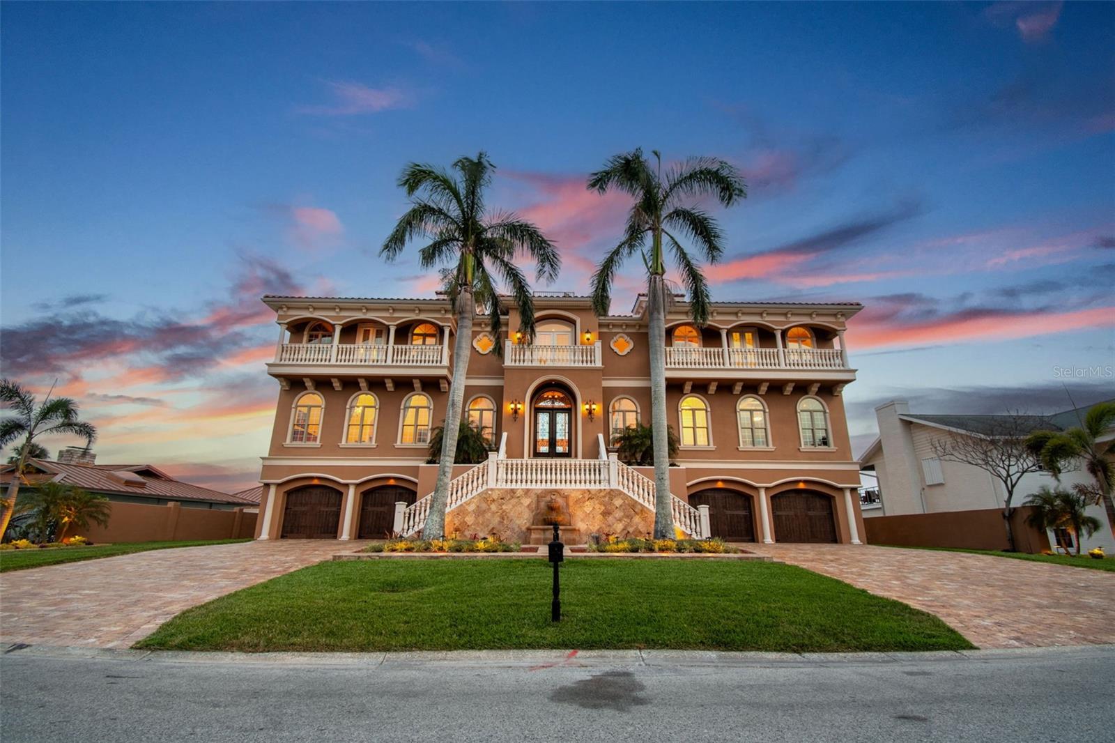 Welcome to an extraordinary Mediterranean-inspired waterfront estate, perfectly positioned on open water in South Tampa. Designed for those who seek sophistication, comfort, and sweeping waterfront vistas, this grand residence blends timeless elegance and modern luxury in one of Tampa Bay’s most in-demand locations.
From the moment you arrive, you’re greeted by a stately façade reminiscent of a Tuscan villa—idyllic fountain, grand staircase, and oversized wood doors set the tone for what’s inside. Step into the main living area and be captivated by soaring 24-foot ceilings and unobstructed views across Tampa Bay. The main living area sits on the third level for the ultimate in enhanced water views, privacy, and security. The expansive great room showcases floor-to-ceiling impact-rated windows and French doors that fill the home with natural light while offering panoramic views. Step through one of three sets of French doors onto a spacious covered balcony overlooking the outdoor oasis, highlighted by a one-year-new beach-entry pool and spa, travertine patio, and a custom pergola with a rain waterfall feature that creates a serene setting for relaxation and entertaining. The travertine patio extends to the seawall, which was completely rebuilt three years ago and includes a travertine cap for a seamless look. With a deep 14-foot channel, this home is ideal for accommodating larger boats—there is ample space to build an extended dock or utilize the marina around the corner. Just off the great room, the formal dining room boasts tray ceilings and an elegant ambiance for entertaining. The luxury kitchen is a chef’s dream, equipped with top-of-the-line appliances, custom cabinetry, a large island, walk-in pantry, and a sun-drenched breakfast area overlooking the water. This level also includes a richly appointed home office with custom wood built-ins and a spacious den with a full wet bar—perfect for hosting and relaxing against a backdrop of open-bay beauty.
The fourth level hosts the primary suite—a luxurious retreat featuring a private balcony with expansive water views and stunning sunsets. The spa-inspired bathroom exudes elegance, featuring a deep soaking tub for ultimate relaxation, an expansive walk-in shower with upscale finishes, and a generously sized walk-in closet designed for boutique-style wardrobe organization. Across the split level are two additional ensuite bedrooms—both with private balconies and breathtaking views. Crowning the home is a top-level observation deck, where you can enjoy panoramic views and sunset cocktails with friends.
Below the main living areas, the second level is designed for flexibility and privacy, featuring an additional entrance, a full kitchen, two bedrooms, two bathrooms, and a large open-concept living/media room—perfect as an in-law suite or additional entertainment area large enough for a TV area, pool table and a poker or air hockey table. The home features a split garage configuration on the ground level, each side with epoxy floors, accommodating four full-sized vehicles plus room for an additional compact car (or more with the addition of a lift). The climate-controlled garage—complete with soaring 10-foot ceilings—is a rare offering for the discerning automotive enthusiast. A hydraulic elevator provides convenient access to all floors. This home was engineered for coastal resilience—all doors and windows are impact-rated, and a new roof was installed in 2025 for added peace of mind.