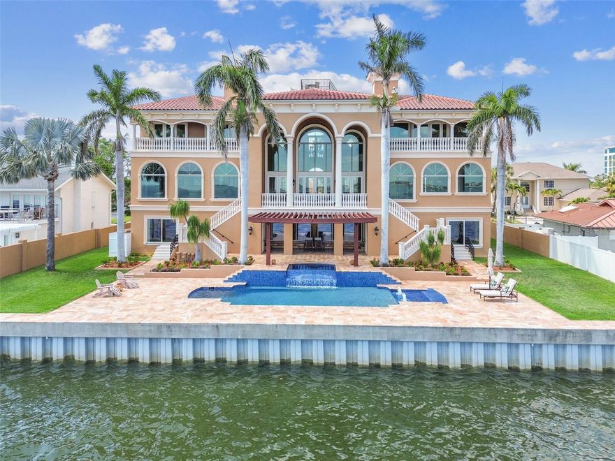 Welcome to an extraordinary Mediterranean-inspired waterfront estate, perfectly positioned on open water in South Tampa. Designed for those who seek sophistication, comfort, and sweeping waterfront vistas, this grand residence blends timeless elegance and modern luxury in one of Tampa Bay’s most in-demand locations.
From the moment you arrive, you’re greeted by a stately façade reminiscent of a Tuscan villa—idyllic fountain, grand staircase, and oversized wood doors set the tone for what’s inside. Step into the main living area and be captivated by soaring 24-foot ceilings and unobstructed views across Tampa Bay. The main living area sits on the third level for the ultimate in enhanced water views, privacy, and security. The expansive great room showcases floor-to-ceiling impact-rated windows and French doors that fill the home with natural light while offering panoramic views. Step through one of three sets of French doors onto a spacious covered balcony overlooking the outdoor oasis, highlighted by a one-year-new beach-entry pool and spa, travertine patio, and a custom pergola with a rain waterfall feature that creates a serene setting for relaxation and entertaining. The travertine patio extends to the seawall, which was completely rebuilt three years ago and includes a travertine cap for a seamless look. With a deep 14-foot channel, this home is ideal for accommodating larger boats—there is ample space to build an extended dock or utilize the marina around the corner. Just off the great room, the formal dining room boasts tray ceilings and an elegant ambiance for entertaining. The luxury kitchen is a chef’s dream, equipped with top-of-the-line appliances, custom cabinetry, a large island, walk-in pantry, and a sun-drenched breakfast area overlooking the water. This level also includes a richly appointed home office with custom wood built-ins and a spacious den with a full wet bar—perfect for hosting and relaxing against a backdrop of open-bay beauty.
The fourth level hosts the primary suite—a luxurious retreat featuring a private balcony with expansive water views and stunning sunsets. The spa-inspired bathroom exudes elegance, featuring a deep soaking tub for ultimate relaxation, an expansive walk-in shower with upscale finishes, and a generously sized walk-in closet designed for boutique-style wardrobe organization. Across the split level are two additional ensuite bedrooms—both with private balconies and breathtaking views. Crowning the home is a top-level observation deck, where you can enjoy panoramic views and sunset cocktails with friends.
Below the main living areas, the second level is designed for flexibility and privacy, featuring an additional entrance, a full kitchen, two bedrooms, two bathrooms, and a large open-concept living/media room—perfect as an in-law suite or additional entertainment area large enough for a TV area, pool table and a poker or air hockey table. The home features a split garage configuration on the ground level, each side with epoxy floors, accommodating four full-sized vehicles plus room for an additional compact car (or more with the addition of a lift). The climate-controlled garage—complete with soaring 10-foot ceilings—is a rare offering for the discerning automotive enthusiast. A hydraulic elevator provides convenient access to all floors. This home was engineered for coastal resilience—all doors and windows are impact-rated, and a new roof was installed in 2025 for added peace of mind.