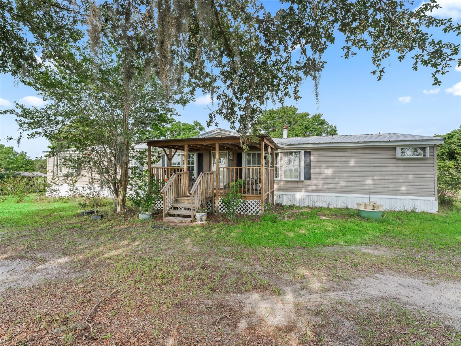 PRICE IMPROVEMENT!!!
A new home awaits you, and you just found it, sitting on 5 acres. Step into a world of tranquility with this spacious 2,333 sq. ft. home that’s perfect for families and nature lovers alike! Featuring 4 inviting bedrooms with a generous size den that could be a 5th bedroom, also included are 2 well-appointed full baths. This residence offers an abundance of space, a massive living room with a fireplace and a family room that’s ideal for gatherings. Imagine sipping your morning coffee while seeing the sunrise on the charming covered front porch while soaking in stunning views or unwinding with the view of a beautiful sunset and enjoying the evenings surrounded by the beauty of nature. The expansive master suite boasts a generous walk-in closet and a beautifully updated en-suite bathroom featuring a claw foot tub, ensuring your personal retreat is both relaxing and functional. This home has laminate flooring throughout and vinyl in the kitchen and bathrooms, and it is designed for easy living. The eat-in kitchen flows seamlessly into the family room, making it the heart of the home. This mini farm is fully fenced with No Climb Horse fencing and thoughtfully divided for optimal pasture management. Animal lovers will appreciate the three-stall Shed Row Barn, complete with 12x12 stalls, a custom chicken coop, a custom doghouse, and an additional run-in shelter for your furry friends. Enjoy beautiful sunrises and sunsets year-round! This property is conveniently located in a nice country setting but yet minutes away from all the amenities the city has to offer.
There is a second mobile home (2008) 2/2 on property with separate power, well & septic (installed 2019). It is in need of TLC which is reflected on the list price, and it is livable! This one also has additional fenced in area with goat barn and another custom chicken coop.
Experience the best of both worlds with a serene country lifestyle, all just 2.5 miles from restaurants, shopping, gas stations, post office dining, entertainment, healthcare, The Villages and more... Don’t miss out on this unique opportunity to embrace the farm life you’ve always dreamed of—schedule a visit today! You will not be disappointed.