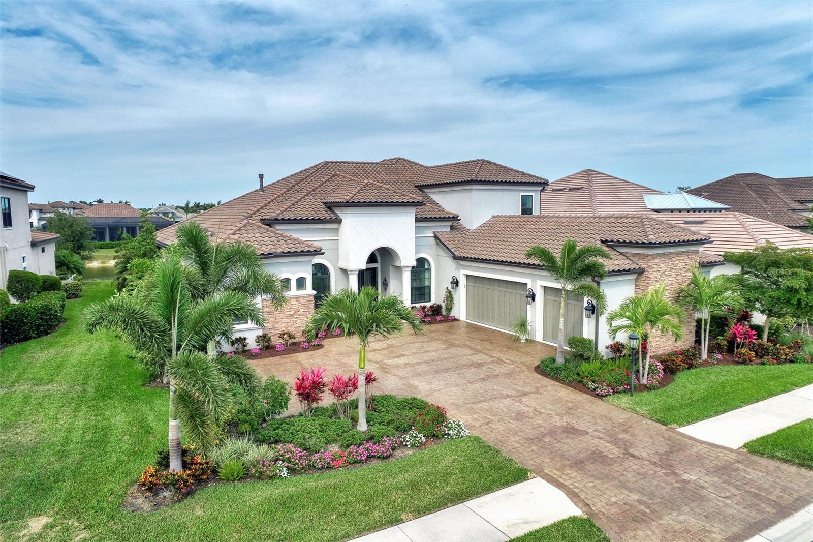 Rarely Available Mercedes Model home on the Legacy side of Esplanade on Palmer Ranch with gorgeous dual lake views. Beautiful sunsets that glisten over the front lake and gorgeous orange color sunrises over the back. Elegantly decorated with exquisite chandeliers, crown molding, tray ceilings, travertine flooring, quartz countertops, and soaring 12 foot ceilings -this home boosts CLASS! Over 4400 square feet of living area - 4 bedrooms, 4 full baths and 2 half baths with each bedroom having its own ensuite for privacy and a large upstairs bonus room with wet bar for additional entertainment. Gourmet kitchen featuring GE Cafe series stainless steel appliances with double ovens and convection. Solid wood cabinetry. Large quartz island to prepare your favorite dishes. Endless cabinet space and pull out drawers. Gas cooking! This modern open floor plan makes its perfect for entertaining with open living room and dining room areas. Enjoy lighting the gas fireplace! The office has french doors and beautiful bamboo flooring, Large master suite with custom walk in closets. Step outside thru the vanishing pocket sliding glass doors onto your extended large covered enclosed wide screen view lanai overlooking the back lake. Experience a taste of Florida lifestyle - Swimming in your heated pool, soaking in the spa or maybe grilling using your outdoor kitchen. Wonderful outdoor bar and sitting areas along with an electric outside fireplace for your enjoyment! Meticulously maintained Upgrades include all impact windows and doors, custom closets, large 3 car garage, lush landscaping, new outdoor lighting, garage sink, lawn maintenance and more! Legacy Estates is a gated Taylor Morrison signature community on Palmer Ranch which offers enriched amenities like no other community. It feels like being on a cruise ship! These amenities are a Lifestyle director, elegant amenity center with wellness services, catering kitchen, lounge areas , fitness center & activity rooms, Resort style pool & spa, fire pit, walking trails, private entrance to the Legacy Bike Trail , tennis, pickle ball, bocce, dog parks and its own neighborhood Bahama bar that includes restaurant and full bar. This neighborhood is a fun place to live. Don't miss out on this beautiful house to call home. Golf carts welcomed!