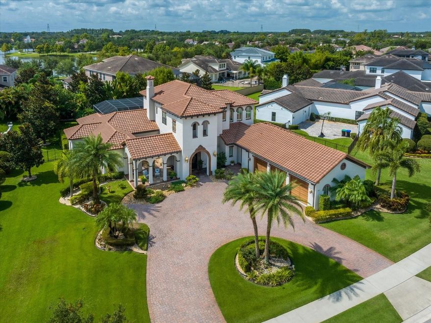 Come home to luxury in your own private oasis with this former model home from the award-winning custom builder, Brierhill Homes located in Windermere’s sought after, guard-gated Waterstone community. This home has 5 bedrooms, 5.5 baths, and a circular driveway with oversized 3-car garage.  From the moment you enter through the 9’ Cantera design arched steel front door you are encompassed by style and elegance.  The formal living room with fireplace and dining room large enough to host the entire family are the center of the home and feature custom columns and exquisite trim work. Truly depicting the "heart of the home" is the chef's kitchen featuring a custom range hood with precast stone & travertine accents above a 36” Professional Series stainless steel natural gas cooktop, exotic granite countertops with travertine backsplash and custom maple cabinets, Thermador appliances and granite top over-sized kitchen table that seats up to 8. Off the kitchen is the wine cellar with decorative wrought iron door and a wet bar area with refrigeration.  The primary suite boasts tranquility with a large custom closet and bath with garden tub, shower, dual sinks and a vanity area.  The office adjoins the primary suite and has a separate outside entrance with a courtyard and front porch. There is a second bedroom ensuite on the first floor with spacious closets, a mud area and oversized laundry room that has an abundance of cabinets and space for a full-size refrigerator. Making your way upstairs via the spiral staircase with travertine treads you enter the loft/sitting area and three additional ensuite bedrooms with spacious closets.  The oversized fenced back yard has mature landscaping that provides a private sanctuary with an outdoor kitchen, pool bath and fireplace accompanying the screened lanai with wood paneled ceilings and travertine deck. The screened saltwater pool/spa has a swim shelf, relaxing fountain and both the pool and spa can be heated. This home has so many amazing features including the disappearing edge glass sliders in the family room that access the pool deck, hand-stained ceiling beams in the kitchen, wide plank walnut wood and travertine floors throughout, Restoration Hardware lighting, tankless gas water heaters, built-ins throughout, whole house audio inside and out, plantation shutters, and worry-free living with your whole-home Generac backup generator. Conveniently located around the corner from Windermere Preparatory School with private community access, Windermere High School, minutes from Disney, shopping, dining, and all that Central Florida has to offer.