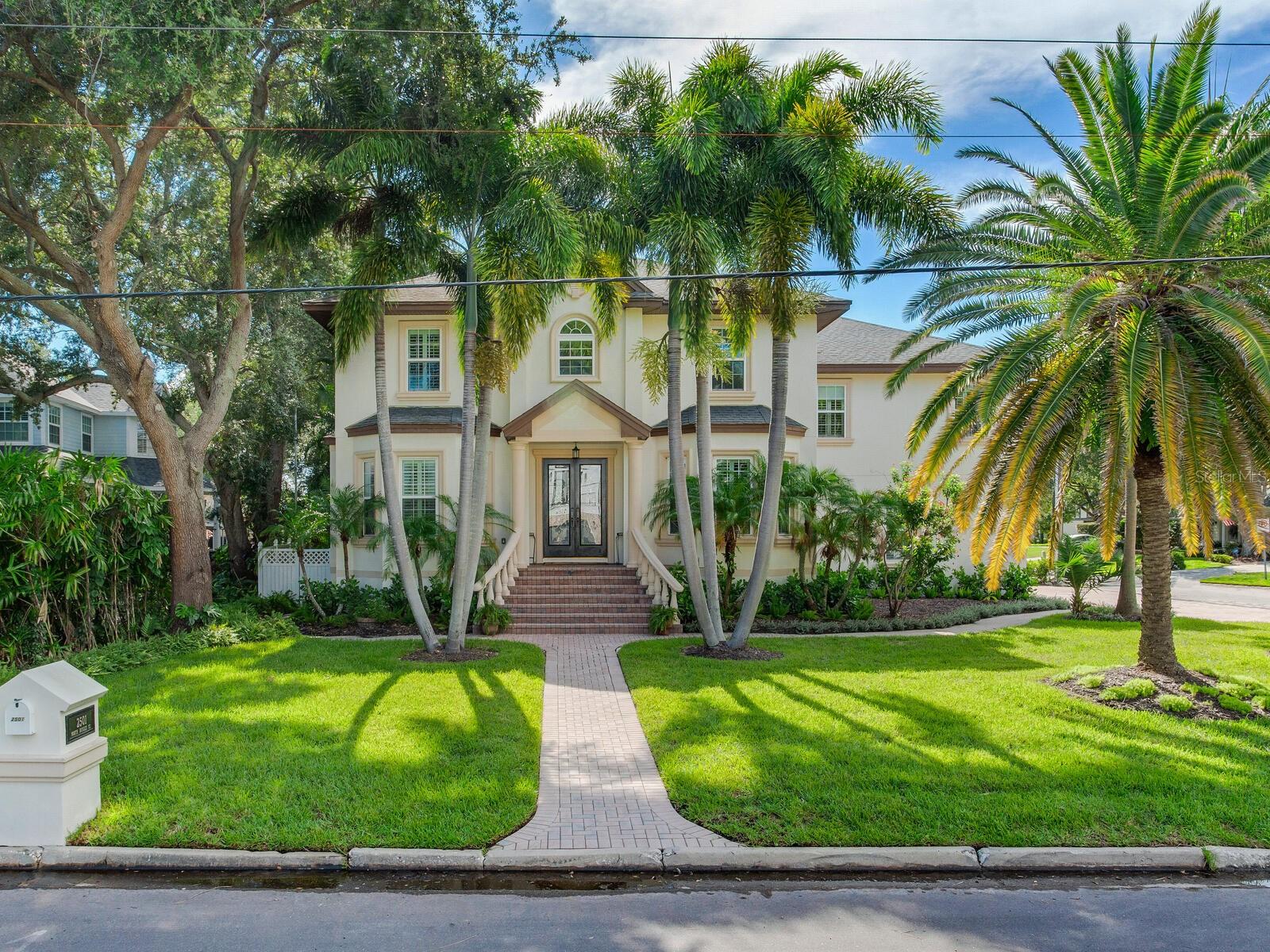 Located on a beautifully landscaped corner lot, this elevated and stately 4-bedroom and 3.5-bathroom home presents with a stunning front staircase, wood-framed leaded and beveled glass French entry doors, and symmetrically placed arched windows outlined with decorative molding. The Florida friendly landscaping completes this picturesque setting. On entering the foyer, you will be taken with the beautiful inlaid classic grey hardwood flooring, the soft glow from the LED lighting, the striking light fixtures, and the clean and uncluttered style. Other features include formal living and dining rooms, an office with built-in shelving, a large family room, a well-appointed kitchen with gas and electric ovens, a dining nook and central island, and a large sub-zero wine cooler. The built-out pantry, butler’s pantry, utility room, and under stair storage are other functional features. The back porch overlooks an inviting gazebo. On the second floor, a large media room is equipped with 3 mounted TVs and a wet bar. The primary bedroom is a spacious and inviting retreat. The primary bathroom is fabulously remodeled and exquisitely upgraded. Bathroom features include porcelain flooring and a floor to ceiling wall of white and black porcelain that extends behind the steam shower, the stand alone jacuzzi tub, and the opaque glass water closet with a Kohler all-in-one bidet. The long double sink vanity is adorned with contemporary and handsome mirrors and light fixtures. The other bedrooms are a considerable size and have built-in closets. Be sure to ask for a fact sheet that includes a list of other upgrades. Located in Sunset Park Isles. It enjoys easy access to Tampa International Mall, Tampa International Airport, the Westshore business district and Tampa’s best private and public schools. Entertainment, sports, and dining venues are close by. Pool is possible. Be sure to see the proposals for a pool in the attachments