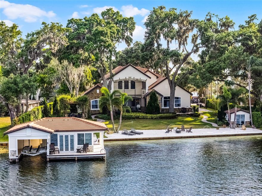 Welcome to perhaps the best outdoor location on the entire Butler Chain with a nearly 300 square-foot-enclosed boathouse, custom beach and a fully landscaped yard with plenty of space and enhancements for entertainment.   The outside space includes hot tubs, 170 square-foot outdoor gym, uniquely designed pool with back of the home built around it, over 100+ outdoor lights (multiple underwater lights), built-in water show attached to the sea wall, a pergola wrapped with wisteria vines, mist system for eliminating unwanted Florida flying friends, 8-speaker plus sub sound system and all of which is perfectly designed to complement the over 122 feet of pristine sandy water frontage on Wauseon Bay on the famed Butler Chain of Lakes.  The inside is stunning as it underwent a complete seven figure plus remodel with Sorenson Construction during 2019-2020.  Throughout much of the home there are Restoration Hardware Chandeliers and drapes, Sonos operated speakers, wood shutters and hard wood floors.  The kitchen includes top-of-the-line appliances, Busby cabinets, Cabria Stones, motorized garbage, secret pantry, mini-bar, touch activated faucet and a custom-made copper hood with pot filler underneath.  The custom family room design has a gas fireplace that can vent inside or out, built-in sound system and tailor-made trace ceiling.  The home includes a library with all custom-built cabinets and ladder system by Busby.  The master bathroom includes his and her sections, Busby cabinets, spacious soaking tub and a steam unit shower with four shower heads and bench.  The upstairs boasts an adult game room complete with a custom wood ceiling, five TV’s and poker room and a completely themed room that includes a chalk board, bed, slide, ball-pit, stage, multiple TV’s with gaming systems and plenty of storage. The renovation also included the 3-car garage, which has lots of storage with cabinets and slat walls.  The home includes a partial home generator, newer septic field as of 2024 and newer tile roof as 2020.  From this home you can easily walk or golf cart to Downtown Windermere, Palmer Park or just stay at home and enjoy the view and arguably the best boathouse and backyard space on the Butler Chain.