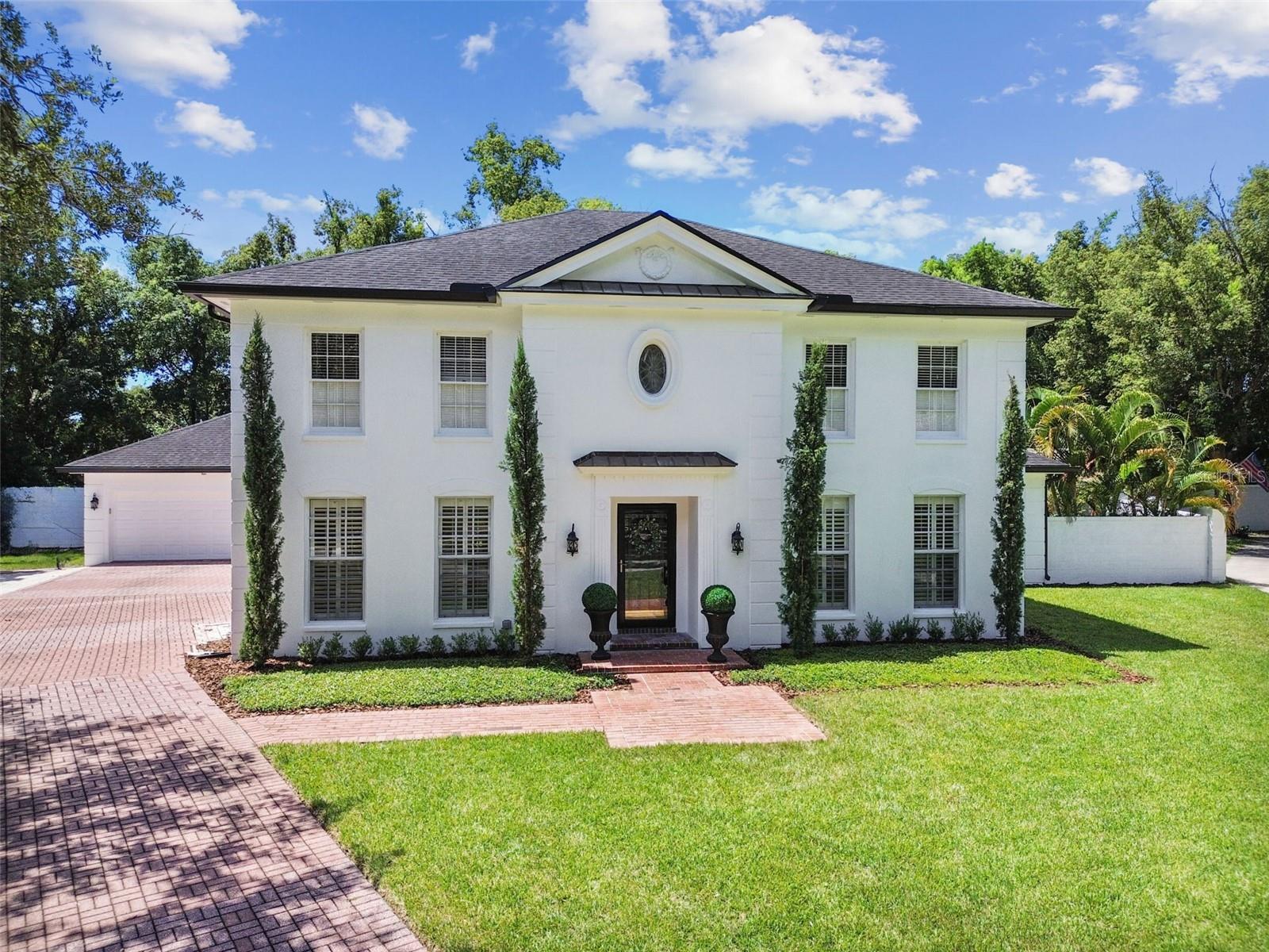 Welcome to this Georgian-inspired estate, gracefully nestled on a private cul-de-sac in the sought-after Thompson East neighborhood, exuding timeless elegance with its classic lines and stately curb appeal. Tall, narrow cypress trees enhance the symmetry, while the brick walkway and driveway lead to an oversized detached garage, thoughtfully positioned to the side and rear to preserve the home’s formal street presence. Beautifully designed and meticulously maintained, the home offers over 3,500 square feet of modern sophistication, featuring four spacious primary bedrooms, each with its own en-suite bathroom, and a total of 4.5 baths. The layout includes a first-floor primary suite with serene views, private access to the pool, and a spa-inspired en-suite bath with a sleek frameless glass walk-in shower, making it ideal for multigenerational living or a private guest retreat. The timeless staircase with a curved banister makes a grand first impression in the foyer. A massive study provides flexible space, perfect for a playroom, office, Pilates room, or gym. At the heart of the home is a gourmet chef’s kitchen featuring a generous center island finished in high-end quartz, ventless cooktop with integrated downdraft, stainless steel appliances, double ovens, floor-to-ceiling custom cabinetry, and a charming breakfast nook. The kitchen opens to a spacious living area, perfect for entertaining, highlighted by detailed wainscoting, crown molding, and abundant natural light. Just off the kitchen, the formal dining room impresses with a stunning crystal chandelier set into an ornate ceiling medallion, an arched built-in niche, and plantation shutters that offer both privacy and classic Southern charm. The first floor showcases wide-format wood-look tile, offering the aesthetic of hardwood with the resilience of tile, while the second-floor features bamboo hardwood flooring that enhances the continuity and character of the upper-level suites. Upstairs, the second-floor primary suite boasts a large custom walk-in closet with center island storage and a luxurious bathroom with a soaking tub and dual showers with marble floors, creating a true owner’s sanctuary. Step outside to your private backyard oasis, featuring a covered lanai, resort-style pool and spa, lush landscaping, and a fully fenced yard complete with a custom wooden playset ideal for outdoor fun. Tucked away on a quiet, tree-lined street with quick access to Whole Foods, Fresh Market, excellent restaurants like Sacred Pepper, top-rated schools (hello, Carrollwood Day School!), major highways, and, for avid golfers, Avila and Carrollwood Country Club. This property offers the true feel of an estate with the warmth of home. This residence seamlessly blends architectural character, modern luxury, and an unbeatable location offering a rare opportunity to call home in Thompson East. Schedule your private showing today!