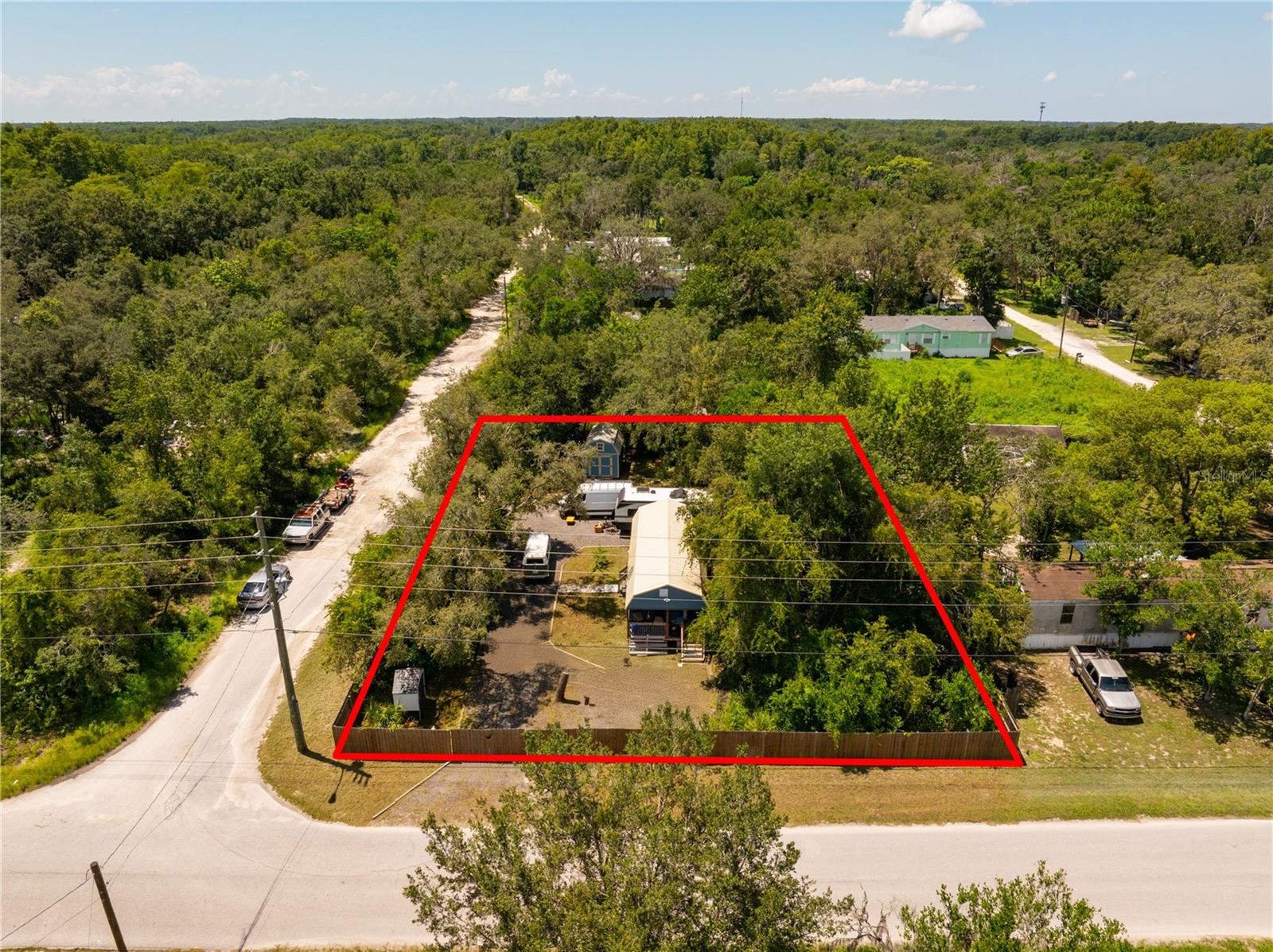Serene Moon Lake Retreat – Ready for Your Mobile Home, RV, or Investment Vision. Escape the hustle and embrace tranquility with this beautifully prepared slice of rural Florida paradise. Located in the peaceful Moon Lake subdivision, this agricultural-zoned property is ideal for those seeking a nature-filled lifestyle or a smart investment opportunity. Whether you're planning to bring in a mobile home, park your RV, or simply enjoy a quiet retreat, this land offers incredible versatility and value. Behind the six-foot wooden privacy fence lies a well-appointed 16' x 40' workshop that’s been upgraded with all the comforts of home. It features a full kitchen complete with range, oven, and residential refrigerator, a beautifully tiled bathroom with tankless water heater, washer and dryer, new vinyl flooring, and two loft spaces for storage or creativity. This property is well-equipped for modern living. A dedicated well with water softener ensures clean, fresh water, and is housed in its own protective shed. Buried power lines feed a 200-amp electrical box—ready to handle anything you bring in—with a 30-amp RV hookup, water spigot, and septic clean-out connection already installed for your convenience. The 900-gallon septic tank can support a modular or mobile home, giving you even more flexibility. A spacious crushed asphalt driveway with dual gated access points makes entry easy for larger vehicles. There's also a large storage shed with power and water connections closely located, perfect for equipment or extra gear. Currently home to a local honeybee business and surrounded by the untouched beauty of Florida’s natural landscape, this property is a true hidden gem. Don’t miss out on this unique opportunity to own a ready-to-enjoy rural retreat. Schedule your private tour today!