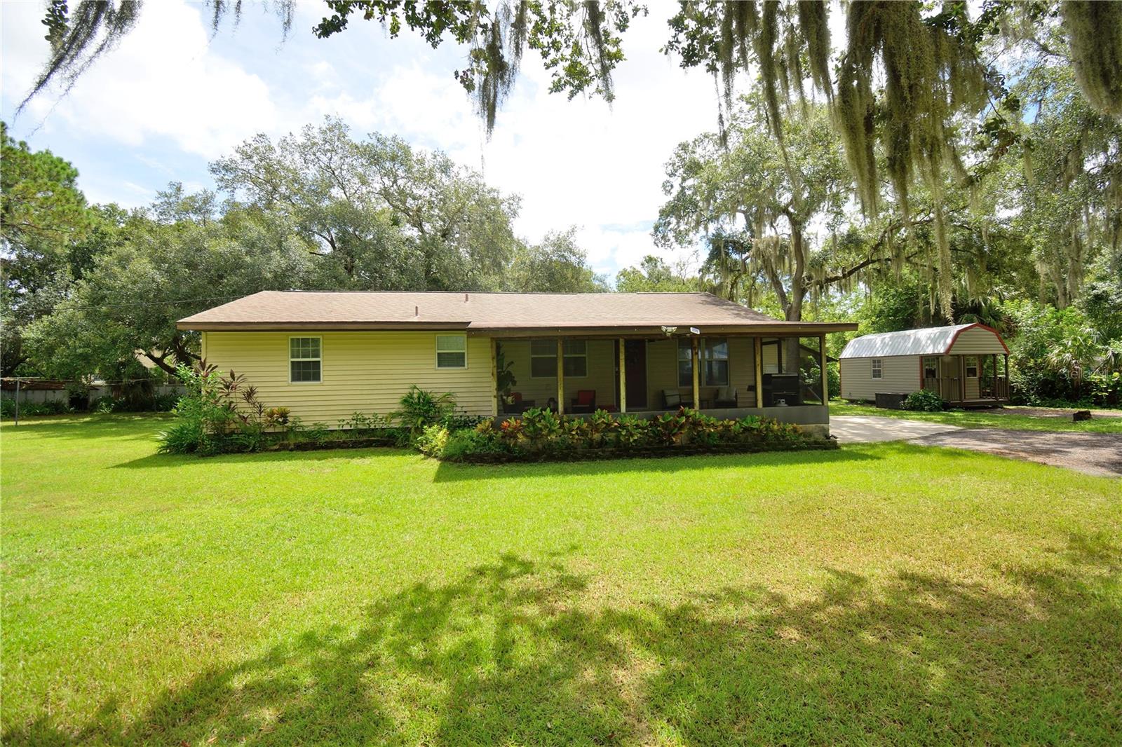 This 4-bedroom home sits on almost an acre with no HOA! This well-cared-for split-level offers over 2,000 sq ft of living space surrounded by shady oak trees with Spanish moss gently swaying in the breeze — a true Ol' Florida vibe. Kick back on the oversized screened patio with a cold iced tea and watch nature play in your front yard. Inside, the spacious family room with original fireplace has plenty of room for TV and game setups. The easy-to-navigate kitchen features stainless steel appliances. There is a detached 624 sq ft building that is a blank slate — perfect for a workshop or converting into an ADU or a garage. With .92 acres, you've got plenty of space for vehicles, boats, or an RV. Enjoy privacy and a large lot while still close to 520, I-95, KSC, shopping, dining, and the beaches.