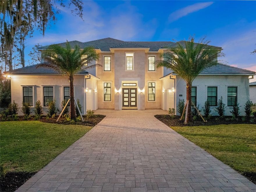 In the upscale Bella Collina community, Four Oaks stands as the epitome of grandeur and sophistication, seamlessly blending opulence with contemporary design. Upon entering, the grandeur of Four Oaks unfolds with a double glass staircase adorned with an impressive modern chandelier that captivates the eye. The unobstructed view from the entryway reveals a breathtaking panorama of the stunning swimming pool and Lake Sienna, the fifth largest lake in Florida, providing a picturesque backdrop to the entire estate. The journey continues into the heart of the mansion, where the double-height ceilings usher you into an extraordinary living room, an elegant dining area and a gourmet kitchen. The kitchen, a culinary haven, boasts an oversized pantry, a professional-grade gas stove, and immaculate cabinetry and countertops. The soothing monochromatic tones throughout the home create an atmosphere of opulence, transforming it into a tranquil oasis. The spacious owner's suite is a sanctuary of luxury, featuring tray ceilings that frame exquisite water views. The adjacent primary bath is equally impressive, offering dual closets and vanities, along with a luxurious Jacuzzi tub adorned with an elegant glass roses chandelier. Four other bedrooms with en suites, each appointed with fandeliers, ensure that every corner of this home exudes comfort and luxury. This turnkey residence boasts essential and luxurious features, tasteful furnishings and impressive upgrades, elevating it to the pinnacle of refined living. This home also features a loft, an office as well as an incredible and spacious library with outstanding lake views and breathtaking sunsets. The outdoor spaces are equally captivating, with retractable custom screens, a summer kitchen, pool and jacuzzi creating an alfresco haven. The artificial grass surrounding the outdoor oasis not only enhances the aesthetic appeal but also ensures maintenance-free living. The expansive lot provides ample space between the house and the lake, allowing the possibility of building a dock to further enhance the waterfront experience. Four Oaks transcends the definition of a mere home, it is a luxurious masterpiece that redefines the art of sophisticated living.