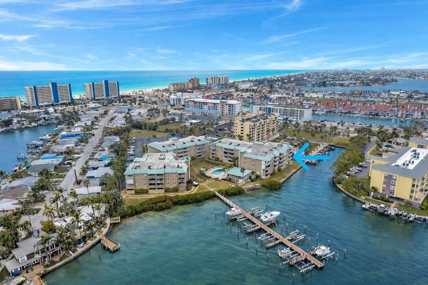 Welcome to this exceptional waterfront three-bedroom corner unit located on the second level of the highly sought-after Madeira Cove condominium. This residence offers abundant natural light, with impact-rated windows on three sides, including a unique bay window in the dining area, distinguishing it from interior units. Upon entry, a welcoming foyer leads to a hallway and spacious living areas, featuring attractive, durable bamboo flooring. The open-concept layout includes a combined living and dining room, alongside a kitchen with a breakfast bar that seamlessly connects to the main living space. Sliding doors from the living room open onto an expansive covered balcony, providing picturesque water views and frequent sightings of dolphins in the bay.The kitchen is equipped with ample maple wood cabinetry, granite countertops, a pantry, and an adjacent laundry closet with full-sized stackable washer and dryer. The split bedroom plan offers two generously sized bedrooms along the hallway, one with private access to the guest bathroom. The primary suite, situated at the rear of the unit, features sliding doors leading to the balcony and windows overlooking the water, all adorned with plantation shutters. The oversized balcony overlooks Boca Ciega Bay and accommodates both alfresco dining and lounge seating, ideal for enjoying the scenic views.Residents enjoy amenities including a sparkling heated pool and waterfront clubhouse, which houses restrooms, a fitness room, and a kitchen suitable for social events. The community also provides a waterfront grill and picnic area, as well as a covered wrap-around porch with bay views. Private boat slips at the community dock may become available for purchase or rental. Assigned parking beneath the building protects vehicles from the elements, while ample guest parking is available. Additional storage is provided with a closet adjacent to the parking space. Located within walking distance to the beach, residents have convenient access to the Gulf for leisure activities. Madeira Cove is a meticulously maintained, all-ages community managed by a proactive association.