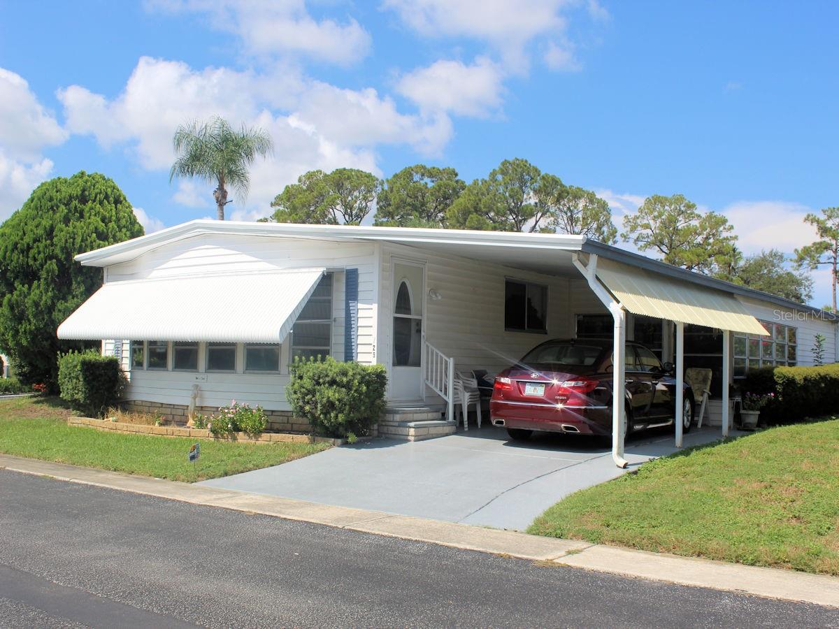 This generous size two bed, two bath manufactured home (1344 sq ft) located on a spacious corner lot in Palm Hill Mobile Home Park awaits new owners. Also, the roof over and gutters new in January of 2025 has a transferable warranty. It’s a short walk to one of the community’s clubhouses complete with updated pool and hot tub. This well-regarded 55+ community offers numerous opportunities for engagement, supported by an inviting and sociable atmosphere. The well thought out monthly fee of $554 includes water, sewer, lawn care, trash, recycle, and even cable and internet. Upon entry, the features of the property that have been maintained by the longtime owner are apparent. The open floorplan makes it easy to move effortlessly from space to space. The furnishings will remain with the home. The owner will be taking only personal items. The circular kitchen has updated light cabinets and countertop with a striking backsplash. Appliances include refrigerator, double sink, smooth top range and overhead microwave. The Counter offers a convenient location for guests to enjoy light refreshments. From the kitchen the floorplan moves comfortably to the sit-down dining area. A built-in display area and spacious drawers are located behind the table. The transition from the dining room to the roomy living room is very smooth. Large windows filter light to the inside. Beyond the living room there is 288 sq ft of additional living space which could be a separate family room. Front windows and a built-in bar offer a comfortable area to unwind. There is an attractive exterior door. The primary bedroom situated at the back of the home has a walk-in closet. The ensuite bath has a door separating the shower and toilet from the rest of the bath. The guest bedroom is situated opposite the hall bathroom and features ample closet space. Ceiling fans in both bedrooms and the front family room distribute air through the home. The home features a five-year-old four-ton A/C system. Ceilings are freshly painted. Furnishings will stay for the new buyer. The exterior is clean and neat. The white siding, dark shutters, new roof over, and a side extension on the carport are appealing. Off the carport there is a lowered bonus room with utility shed featuring washer and dryer. The list price of this furnished, corner lot manufactured home includes the share of $35,000. To see this fine home call for an appointment.