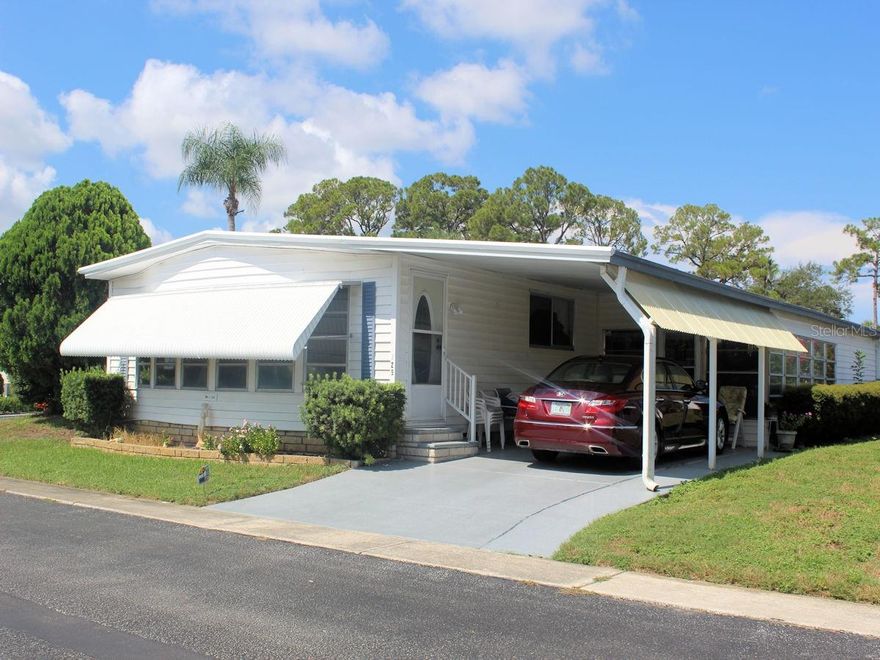 This generous size two bed, two bath manufactured home (1344 sq ft) located on a spacious corner lot in Palm Hill Mobile Home Park awaits new owners. Also, the roof over and gutters new in January of 2025 has a transferable warranty.  It’s a short walk to one of the community’s clubhouses complete with updated pool and hot tub. This well-regarded 55+ community offers numerous opportunities for engagement, supported by an inviting and sociable atmosphere.  The well thought out monthly fee of $554 includes water, sewer, lawn care, trash, recycle, and even cable and internet. Upon entry, the features of the property that have been maintained by the longtime owner are apparent.   The open floorplan makes it easy to move effortlessly from space to space. The furnishings will remain with the home.  The owner will be taking only personal items.  The circular kitchen has updated light cabinets and countertop with a striking backsplash.  Appliances include refrigerator, double sink, smooth top range and overhead microwave. The Counter offers a convenient location for guests to enjoy light refreshments.   From the kitchen the floorplan moves comfortably to the sit-down dining area.  A built-in display area and spacious drawers are located behind the table.   The transition from the dining room to the roomy living room is very smooth.  Large windows filter light to the inside. Beyond the living room there is 288 sq ft of additional living space which could be a separate family room.  Front windows and a built-in bar offer a comfortable area to unwind.   There is an attractive exterior door.  The primary bedroom situated at the back of the home has a walk-in closet. The ensuite bath has a door separating the shower and toilet from the rest of the bath.    The guest bedroom is situated opposite the hall bathroom and features ample closet space.     Ceiling fans in both bedrooms and the front family room distribute air through the home.  The home features a five-year-old four-ton A/C system.  Ceilings are freshly painted. Furnishings will stay for the new buyer. The exterior is clean and neat.  The white siding, dark shutters, new roof over, and a side extension on the carport are appealing.  Off the carport there is a lowered bonus room with utility shed featuring washer and dryer.  The list price of this furnished, corner lot manufactured home includes the share of $35,000.  To see this fine home call for an appointment.
