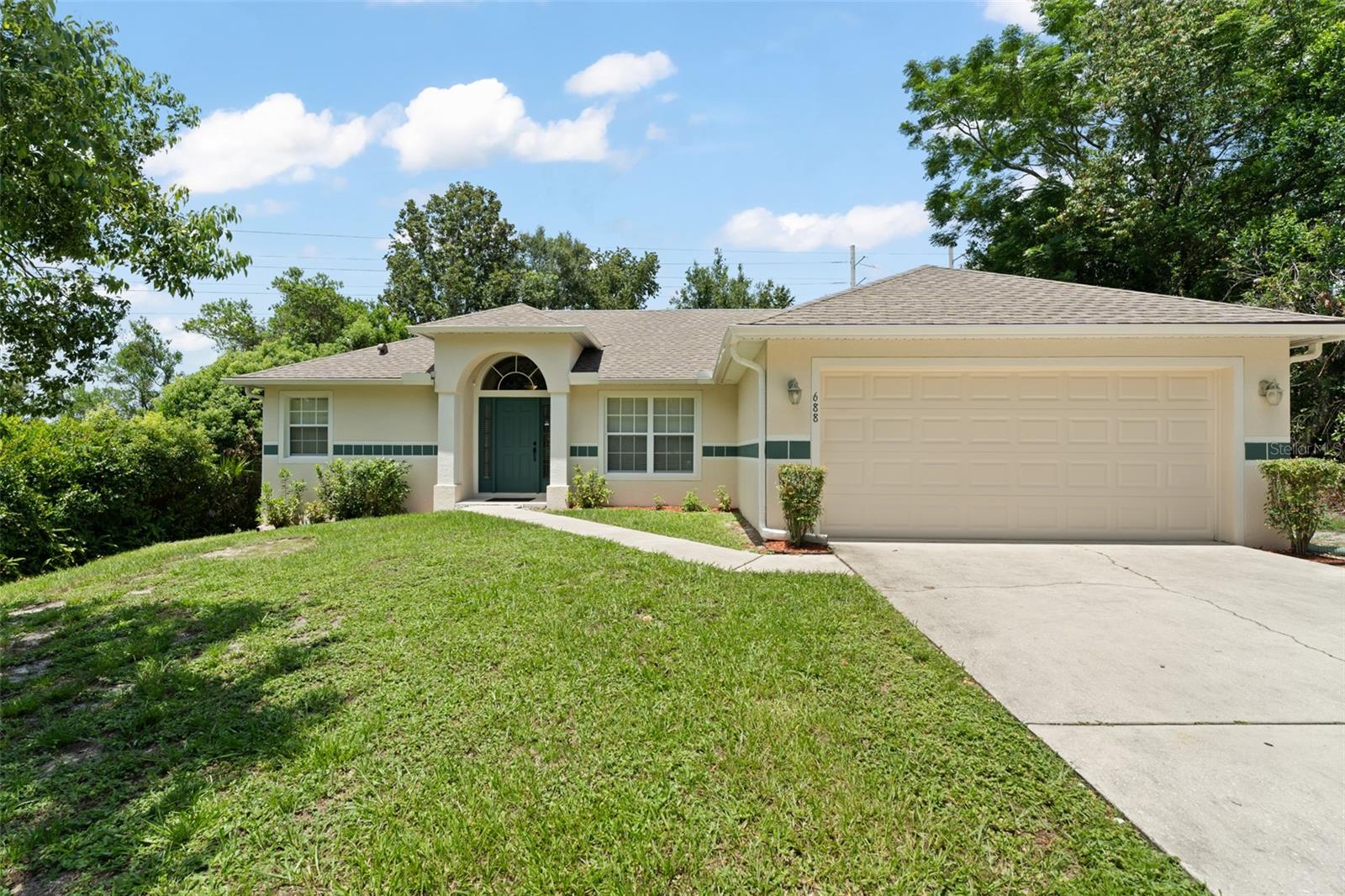 **This property qualifies for a closing cost credit up to $4,800 through the Seller’s preferred lender.**Welcome to a warm and inviting 3-bedroom, 2-bath home with a 2-car garage, nestled in a quiet Deltona neighborhood. From the moment you approach, the charming entryway with dual side lites sets the tone for a home filled with character and comfort. Step inside to a quaint formal living and dining room combo, where elegant wall niches and soaring vaulted ceilings create a cozy yet open atmosphere—perfect for welcoming guests or enjoying quiet moments at home. The thoughtfully designed split-bedroom layout offers privacy and functionality. The primary suite, located to the left of the home, serves as a peaceful retreat featuring a walk-in closet and a spacious ensuite bath with a relaxing corner tub and separate stand-in shower. Just off the garage, the conveniently placed laundry room adds everyday ease to your routine. The heart of the home lies in the open kitchen and family room. With warm-toned cabinets, stainless steel appliances, and a breakfast bar, the kitchen is both stylish and functional. A sliding glass door off the kitchen invites you to step outside and enjoy the covered patio—perfect for outdoor meals, morning coffee, or simply unwinding under the ceiling fan as you take in the serene views. Down the hall from the family room, you'll find two additional bedrooms with built-in closets and a second full bathroom just steps away—ideal for family, guests, or a home office setup. Outside, the spacious backyard is a blank canvas ready for your vision—garden, play area, or future pool—there’s room for it all. Filled with charm and potential, this home offers a place to create lasting memories and call your own.