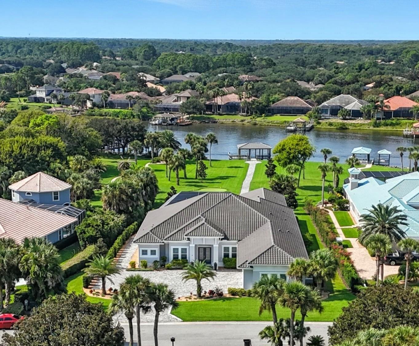 Step into the most exclusive community in Flagler County — Island Estates at Hammock Dunes! This private island enclave is a rare sanctuary where luxury, privacy, and the ultimate Florida lifestyle converge. Completed in 2022, this extraordinary estate is designed for those who dream of boating from their backyard, practicing golf on their own greens, and hosting unforgettable gatherings against a breathtaking waterfront backdrop.
From the moment you pass through the double entry doors, sweeping views of the Intracoastal Waterway set the tone for the home’s elegance. Every detail has been thoughtfully curated, and brought to life by master builder Charles Rinek. The open-concept floor plan showcases five bedrooms, four and a half baths, an office, and a private casita, blending expansive entertaining areas with serene private retreats.
At the center of it all is the chef’s kitchen, a true showpiece with Sub-Zero, Wolf, and Cove appliances, a massive island with seating, a stylish mosaic backsplash, and designer pendant lighting. A separate butler’s pantry with Sub-Zero wine storage and a prep sink ensures effortless entertaining. Just steps away, the living room stuns with soaring tray ceilings, a custom feature wall with a sleek fireplace, and wide-plank luxury vinyl flooring that flows throughout the home. The dining room is equally memorable with its dramatic onyx-inspired accent wall and contemporary chandelier, creating a striking backdrop for intimate dinners or grand celebrations.
The owner’s retreat is a sanctuary of its own, featuring two oversized custom walk-in closets and a spa-like bath with dual vanities, quartz counters, and an oversized glass-enclosed shower with dual shower heads. Guest accommodations are equally luxurious, with a private suite and two spacious bedrooms joined by a Jack-and-Jill bath, all designed to comfortably fit king-sized beds. A detached casita adds even more flexibility with its own private entry, bedroom, full bath, and dedicated office.
Outdoors, the property transforms into a private resort. The screened lanai encloses an infinity-edge pool and spa accented by fire bowls and water features, while a sunken firepit creates a dramatic focal point for evening gatherings. Multiple lounging and dining areas, a fully equipped outdoor kitchen, and a built-in misting system make entertaining effortless year-round. Two putting and chipping greens extend the luxury lifestyle, inviting fun between boat rides from your private dock.
The covered dock is a tranquil waterfront escape out of your dreams. The massive space with built-in seating offers sweeping views up and down the Intracoastal. Watch the boats pass by and dolphins at play as you relax in the shade!
Additional features elevate the home’s prestige even further, including a four-car garage with staircase leading to air-conditioned storage above, an EV charging station, a whole-house generator, and an advanced security system. This home is more than a residence — it is a statement of prestige, where every day feels like a coastal retreat and every moment embodies the ultimate Florida lifestyle.