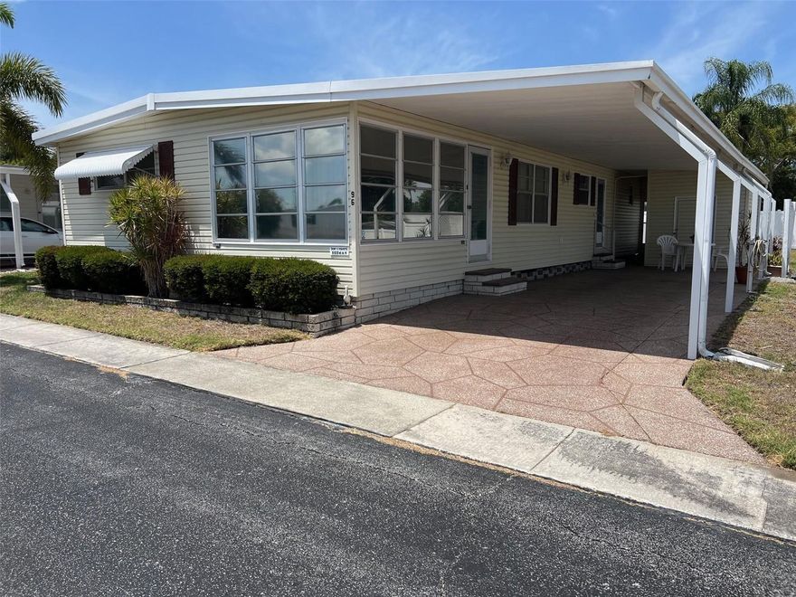Now available on the market, this bright and airy 1,108-square-foot home in Palm Hill Country Club presents an exceptional opportunity to enjoy a sought-after 55+ lifestyle in desirable Pinellas County. The layout of the home includes two bedrooms, each with its own private en suite bathroom, creating a functional living environment. A warm, inviting setting makes it easy to feel at home, and one small pet is welcome to share the space with you. A generously sized yard with no rear neighbors offers a peaceful, open backdrop that’s hard to find. Whether you prefer staying active with golf, tennis, pickleball, or shuffleboard, or unwinding beside the community’s pools and jacuzzis, there’s something for every pace of life. Even better, a combined monthly maintenance fee of $595.00 covers water, sewer, garbage, lawn care, cable, and internet, allowing you to fully enjoy everything this community has to offer without the extra hassle of separate bill-paying!
INTERIOR:
A comfortable and adaptable interior greets you upon entry to this well-designed split floor plan in good condition and enhanced by classic paneled walls, while laminate flooring flows through most of the home. Recent C/H/A (2024), ceiling ducts, and ceiling fans add to the overall comfort. The kitchen features a handy breakfast bar, abundant cabinetry, a pantry, and white appliances, including a refrigerator, range, oven, and dishwasher, while an adjacent dining area showcases a built-in mirrored buffet/hutch with solid cabinetry and glass fronts—perfect for storage and display. The bright, generously sized living room creates an ideal setting for entertaining. At the same time, a charming bonus area with parquet flooring and stylish lighting currently serves as a cozy office but could easily be switched up to fit your vision. The spacious guest bedroom offers a closet and a wall-to-wall built-in dresser, with an en suite bath featuring vinyl flooring, a single vanity, and a tub/shower combination. Additional flexible space is found in the raised Florida room, which could be transformed into an office or even a third bedroom, if desired. The sizable primary suite is filled with natural light and includes a walk-in closet, a built-in dresser, and a private en suite bath complete with a walk-in shower and a large single-sink vanity.
EXTERIOR:
This practical home offers a solid foundation for your Florida lifestyle, featuring durable vinyl siding and a functional coated roof. To help keep the interior comfortable and enhance curb appeal, the home is equipped with awnings. An extended two-car carport provides plenty of shaded parking, while the extra space just beyond it offers a flexible spot for an outdoor seating area to enjoy the Florida breeze! You’ll find added convenience in the utility shed, which houses the washer and dryer together with room for extra storage. Priced at just $85,000 including the share, this is your straightforward ticket into a premier 55+ lifestyle without the premium price tag!  Call soon for your private showing!