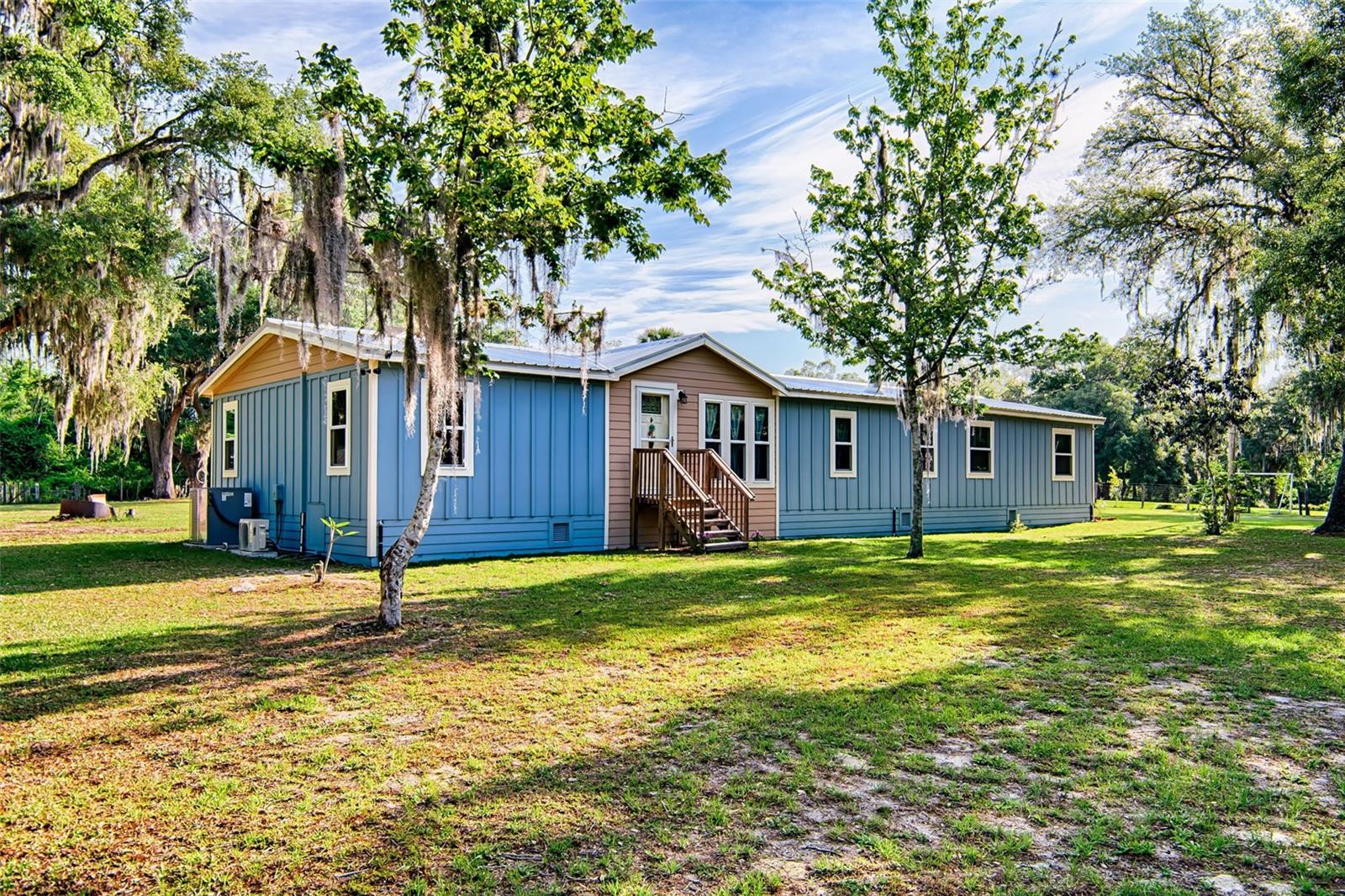 Welcome to this well loved and maintained home on 1.7 acres. This home has been upgraded to last! NEW ROOF, NEW HARDY SIDING and NEW WINDOWS all installed in 2024, less than a year old. The sub-flooring is solid with 3/4" plywood and the spacious kitchen has stone countertops and LG stainless steel appliances. This 1996 mobile home was originally a 4 bedroom/2 bathroom home until the 2 bedrooms at the end of the hallway were combined into one large suite with an opening between them. Enjoy the split floor-plan with two living room areas, one with a wood burning fireplace, where the entire family can spread out and have plenty of space or meet in the dining room attached to the kitchen for easy serving. The large primary bedroom has a boost of cold air from a split unit keeping you cool on the hot Florida summers. Outside you'll find an incredible pole barn used for a carport, two-room shop for all your toys and dry parking for your even bigger toys. It has sufficient electricity hooked up to it and is well lit at night. Turn these lights off to enjoy the bright stars you can only find in the country. The pole barn comes with a generator and compressor. Bring your cows, goats, chickens, etc! The no-climb field fence is great for keeping your animals in the perfect mixture of a grassy and shaded yard. Want more buildings, a mother-in-law dwelling or rental ADU's? The three lots included in this sale are all buildable up to 3 dwellings (1 per lot). On top of all these wonderful things, Fiber internet just got installed on the road! Bring your boat as Lak-a-wana Lake and many others are close by!