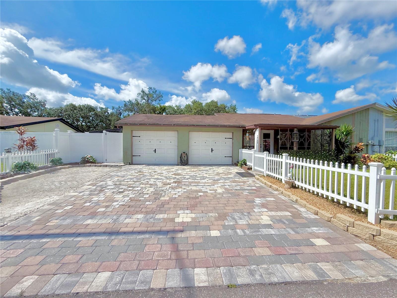 This charming home with tons of upgrades is now available in Town and Country! This 2-bedroom, 2-bathroom offers an ideal blend of comfort and functionality. Situated on a quiet, dead end street, this property boasts an oversized 2-car garage with a 3-car driveway, providing plenty of parking for guests or family. Curb appeal abounds with an adorable front porch, the perfect spot to enjoy your morning coffee. Step inside to an inviting open floor plan featuring vaulted ceilings that enhance the spacious feel of the living and dining areas. The large kitchen consists of lots of cabinets, granite countertops, newer stainless steel appliances, and convenient bar stool seating perfect for casual meals or entertaining. The split bedroom floor plan offers added privacy, with the primary suite featuring an updated en-suite bathroom with walk-in shower. Both bedrooms are generously sized with ample closet space. Enjoy the Florida lifestyle in the screened patio, a perfect space for relaxing or hosting friends. The fully fenced backyard includes a storage shed and has plenty of room for gardening, pets, or play. Some other recent improvements include a roof in 2017, AC in 2025, new LVP flooring, and new interior paint just to name a few. There are no HOA fees, no deed restrictions, or flood insurance required. This home has stayed high and dry! Don't miss your chance to own this move-in ready gem in a fantastic location close to shopping, dining, parks, and major highways.