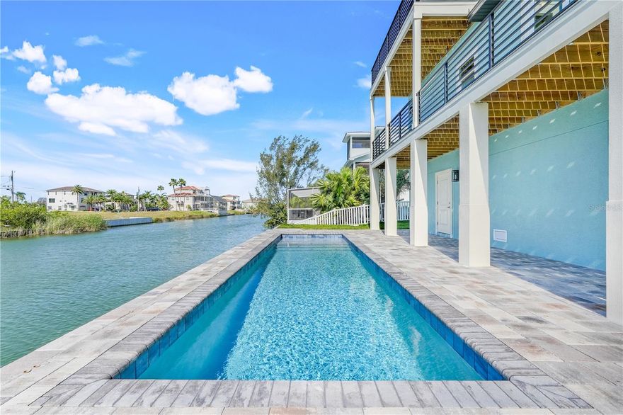 Welcome to this extraordinary 4-bedroom, 3-bath, 3-story waterfront home in the prestigious Hernando Beach South community—where refined craftsmanship meets relaxed Florida living. Designed with elegance, functionality, and lifestyle in mind, this residence offers a rare blend of modern sophistication and timeless charm. From the moment you arrive, you're greeted by an inviting paver driveway, immaculate landscaping, and an elevated covered entry that sets the tone for what lies within. The main entrance features 8-foot custom French doors, leading into a bright and airy interior with hurricane-proof, UV-resistant windows that flood the home with natural light and stunning canal views. There is seamless luxury vinyl plank flooring throughout the main floor. The heart of the home is the gourmet kitchen, where stainless steel appliances, solid wood cabinetry with crown molding, and quartz countertops are complemented by a striking designer tile backsplash and pendant lighting. A spacious island, walk-in pantry, and soft-close cabinetry ensure the space is as functional as it is beautiful. The adjoining dining area creates the perfect setting for hosting elegant dinners or casual family meals. The primary suite is a luxurious escape with a tray ceiling, balcony access, and a large walk-in closet. The spa-like en-suite bath features a frameless glass shower, double sink vanity with quartz countertop, a large soaking tub, and premium finishes. Also on the 2nd floor are two guest bedrooms with their own walk in closest. The laundry room is also on the 2nd floor and offers plenty of space for additional storage. On the third floor you will find an additional bedroom or open office space with the 3rd bathroom and a private balcony. Both guest baths include upscale touches like the Maxx Rubix soaking tub, ideal for relaxing after a day on the water. Outdoor living is just as impressive with a 2nd floor balcony overlooking the pavered pool area and canal. The inground saltwater lap pool is perfect for both recreation and wellness, while the spacious yard still offers room to play. The home also has a 7 car garage for storing your toys, which should include a golf cart for the newly approved golf cart access to the local restaurants in the area. Every detail in this home has been considered—including pre-wiring for an elevator, Moen fixtures, and Trex decking for your steps and balconies. The property’s height-restricted Gulf of America access makes it a dream come true for boating enthusiasts. Whether you're casting a line, hosting a family gathering, or simply savoring the quiet beauty of coastal life, this home has everything you need to live in comfort and style. Don’t miss your chance to experience this coastal masterpiece. Schedule your private showing today and discover the effortless luxury of Hernando Beach South.