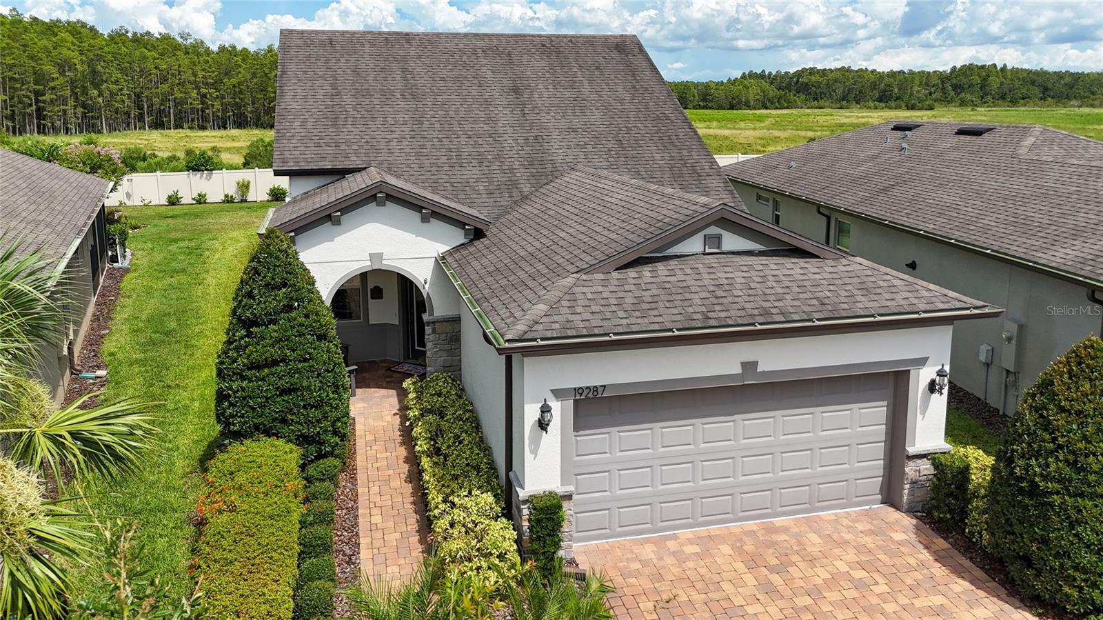 Welcome to this stunning Steel Creek Grand model, perfectly situated in the sought-after gated active over 55 community of Del Webb Bexley in Land O’ Lakes—just minutes from major roads, top shopping and dining, excellent medical facilities, and less than 30 minutes from both Downtown Tampa and Tampa International Airport. From the moment you arrive, the great curb appeal is undeniable, with a brick paver driveway, stone-accented entryway, covered front porch, retractable screen door, and decorative glass inlay front door creating a warm and inviting welcome. Inside, you’ll be greeted by soothing earth tones, wood accent walls, and unique designer light fixtures throughout, with crown molding in every room adding elegance. Luxury vinyl flooring flows through the main living areas, complemented by a staircase with decorative wrought-iron spindles that’s tucked away to preserve the home’s open flow. The heart of the home is the spacious, well-appointed kitchen, featuring a massive quartz island, stainless steel appliances, pull-out shelving, and a custom pantry. Enjoy meals in the sunlit breakfast nook, then transition to the Florida room (not included in square footage) that leads to two screened lanais—one enhanced with perimeter outdoor lighting—perfect for evening gatherings. This well-designed two-story layout features 3 bedrooms, 3 full baths, and a loft. The upstairs offers a private retreat with a bedroom, full bath, and loft—ideal for a guest suite, a grandkids’ playroom, or a home office—complete with built-in surround sound speakers. The primary suite boasts a spa-like ensuite bath with dual sinks, quartz counters, a shower with glass doors, and an exceptional custom-built closet. All closets in the home feature custom built-ins, and the laundry room offers cabinet storage plus an included washer and dryer. The 2-car garage comes with extra storage cabinets that will remain for the new owners. The pie-shaped, oversized backyard provides complete privacy and a peaceful pond view to the left—an ideal spot for morning coffee or quiet relaxation. And with lawn care included, you’ll have more time to enjoy the things you love. If you enjoy staying Active INCREDIBLE AMENITIES include a Resort-Style Pool with lap lanes, Resistance Pool, Hot Tub, and Cabanas, Expansive 19,000 sq. ft. clubhouse, Multipurpose Room and Arts and Crafts Room, Beer and Wine Bar, Cafe/Bistro/, Outdoor Fireplace, Lounge, 2 Tennis Courts, 6 Pickle ball Courts, 4 Bocce Ball Courts, Fitness Center, Movement Studio, Community Garden, Dog Park, and many Resident Clubs and Interest Groups! Whether you're looking for a full-time residence or a second home to escape the cold and snowy days up North, impeccably cared for, this home has it all! Don’t let this one slip away!