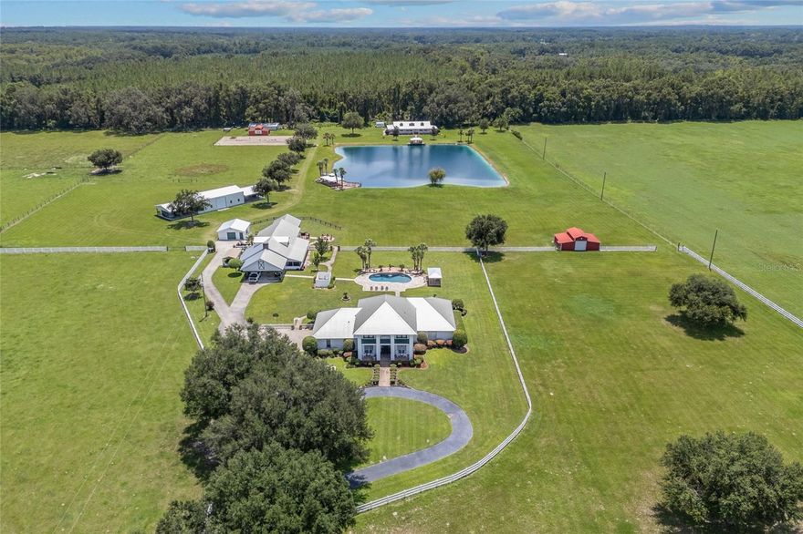 A rare opportunity to own 40 acres of paradise just minutes from town! This one-of-a-kind North Florida estate blends country charm with resort-style living, surrounded by lush green pastures that are fully fenced and cross-fenced for both beauty and function. The main home offers 3 bedrooms, an office (optional 4th bedroom), an upstairs loft, and 3.5 bathrooms. The owner’s suite is conveniently located on the main floor, providing a private retreat for rest and relaxation. Step out back and you’ll find your own private retreat—a gorgeous newly remodeled pool accented by a cascading waterfall, with a paver patio perfect for lounging or entertaining. From there, a charming paver walkway leads to the Barndominium, an entertainer’s dream. Designed for gathering, it features a spacious great room anchored by a cozy wood-burning fireplace, a large kitchen with a generous bar, and dining space both inside and in the screened outdoor room. Upstairs, comfortable guest quarters provide a welcoming space for family and friends. At the rear of the property, a 3-bedroom, 2-bath modular home offers additional living space, perfectly situated to overlook the sparkling stocked pond with its own private deck—an ideal spot for fishing or simply soaking in the peaceful views. Multiple outbuildings, including a 30' x 60' insulated structure, add to the property’s versatility and convenience. A true slice of north Florida paradise, ready to be cherished for years to come!