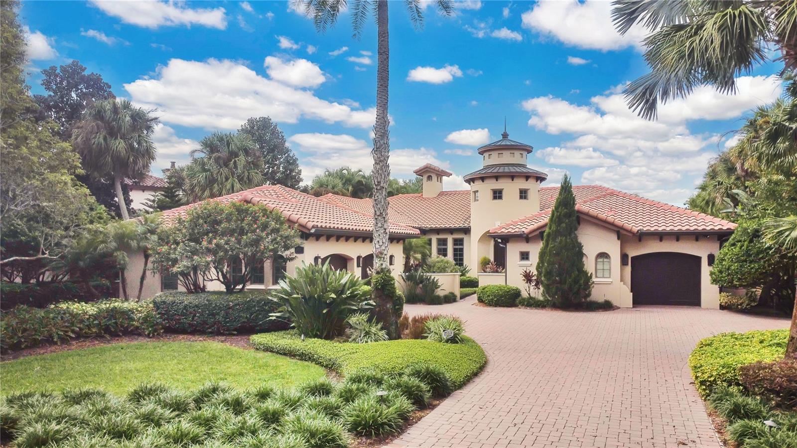 Experience the art of fine living in this exquisite one-story Modern Mediterranean garden villa, offered fully furnished with a curated designer furniture package. Every detail has been thoughtfully crafted, blending timeless architecture with refined finishes and effortless comfort.
Inside, travertine floors, wood-beamed ceilings, and solid wood doors set a warm, sophisticated tone. Custom cabinetry, designer window treatments, and rich textures throughout create a sense of understated luxury. The double island kitchen is a culinary masterpiece, featuring Quartzite countertops, a marble mosaic backsplash, gourmet appliances, a gas stove, wet bar, and butler’s pantry—perfect for both intimate dining and grand entertaining. 
A cast stone fireplace anchors the elegant living room, while the expansive family room opens through panoramic sliding doors to a covered lanai, creating a seamless indoor-outdoor experience.
The primary suite is a sanctuary of indulgence, complete with a morning bar, private sitting area, spa-inspired bath, and generous walk-in closet. A wood-floored study with custom built-ins provides a refined space for work or reflection.
Outdoors, the resort-style setting is framed by lush tropical landscaping and tranquil pond views. The spacious lanai features a summer kitchen and pool bath overlooking a heated saltwater pool and spa—your private oasis for relaxation and entertaining. A three-car garage completes this extraordinary residence, where every element has been designed for the most discerning homeowner. Isleworth is surrounded by the Butler Chain of Lakes and known for its manicured gardens, timeless architecture, and unparalleled privacy. This exclusive guard-gated community offers 24-hour security and the opportunity to join the Isleworth Golf & Country Club featuring world-class golf, tennis, resort-style pool, fitness, dining, and social events. Garden Villas include exterior grounds maintenance for effortless living.