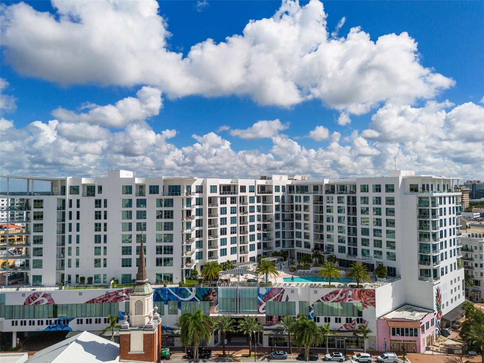 **Furniture Available** Welcome to The Mark, an upscale destination for coastal luxury situated in the heart of historic downtown Sarasota. This vibrant city is known for its cultural richness, diverse arts scene, shopping, and exceptional dining options. Located in the center of the theatre district, the area is home to the Florida Studio Theatre, Sarasota Opera House, and Van Wezel Concert Hall, all within walking distance. A brief stroll will take you to the scenic Bayfront and Marina, where options for boating and waterfront eateries await. As the sun sets, the palm tree-lined streets are illuminated, creating a perfect environment for outdoor dining. The Mark’s prime location ensures that you are just steps away from everything. Residents can conveniently hop on the trolley or ride bikes across Ringling Bridge to discover the natural beauty of Lido Key, St. Armands Circle, and the picturesque Lido Beach. Upon entering The Mark, the sophisticated ambiance of the lobby immediately sets a luxurious tone. Positioned on the 9th floor, this exceptional residence showcases elegance and refinement. The high ceilings and floor-to-ceiling sliding glass doors lead to a spacious balcony, perfect for outdoor entertaining. Enjoy panoramic views of the city with glimpses of the bay to the left, providing a serene backdrop for relaxation. The kitchen is equipped with high-end JennAir stainless steel appliances and veined white quartz countertops, creating a modern and inviting space. Functional design features include a built-in pantry and multiple pull-out drawers, complemented by high-end light fixtures that enhance the home’s luxurious feel. The primary suite is designed with large windows, access to the balcony, and two custom closets. The en-suite bathroom boasts a spacious walk-in shower with Carrara tile that elegantly unifies the shower walls and floor. A private guest suite, complete with a full bathroom, is located on the opposite side of the residence, ensuring comfort for visitors. Both bedrooms are equipped with remote-controlled electric blinds. Additionally, a versatile room with tray ceilings and complete with a closet offers flexibility for use as an office or additional guest room. At The Mark, luxury amenities are meticulously curated to enhance your lifestyle. Residents can enjoy an elevated resort-style pool adorned with private cabanas, umbrellas, and loungers, along with outdoor kitchens, a hot tub, and a cozy fire pit lounge area. The Club Room serves as an ideal venue for hosting events, equipped with a catering kitchen and a bar that opens to the expansive terrace and pool deck. Start your day with a workout in the state-of-the-art fitness center, then head to the farmer’s market for breakfast just a block away. The building offers a range of conveniences, including 24-hour concierge service, resident storage, secured parking, and an access-controlled lobby. The Sarasota lifestyle awaits you at The Mark, where this exceptional residence could be yours.
