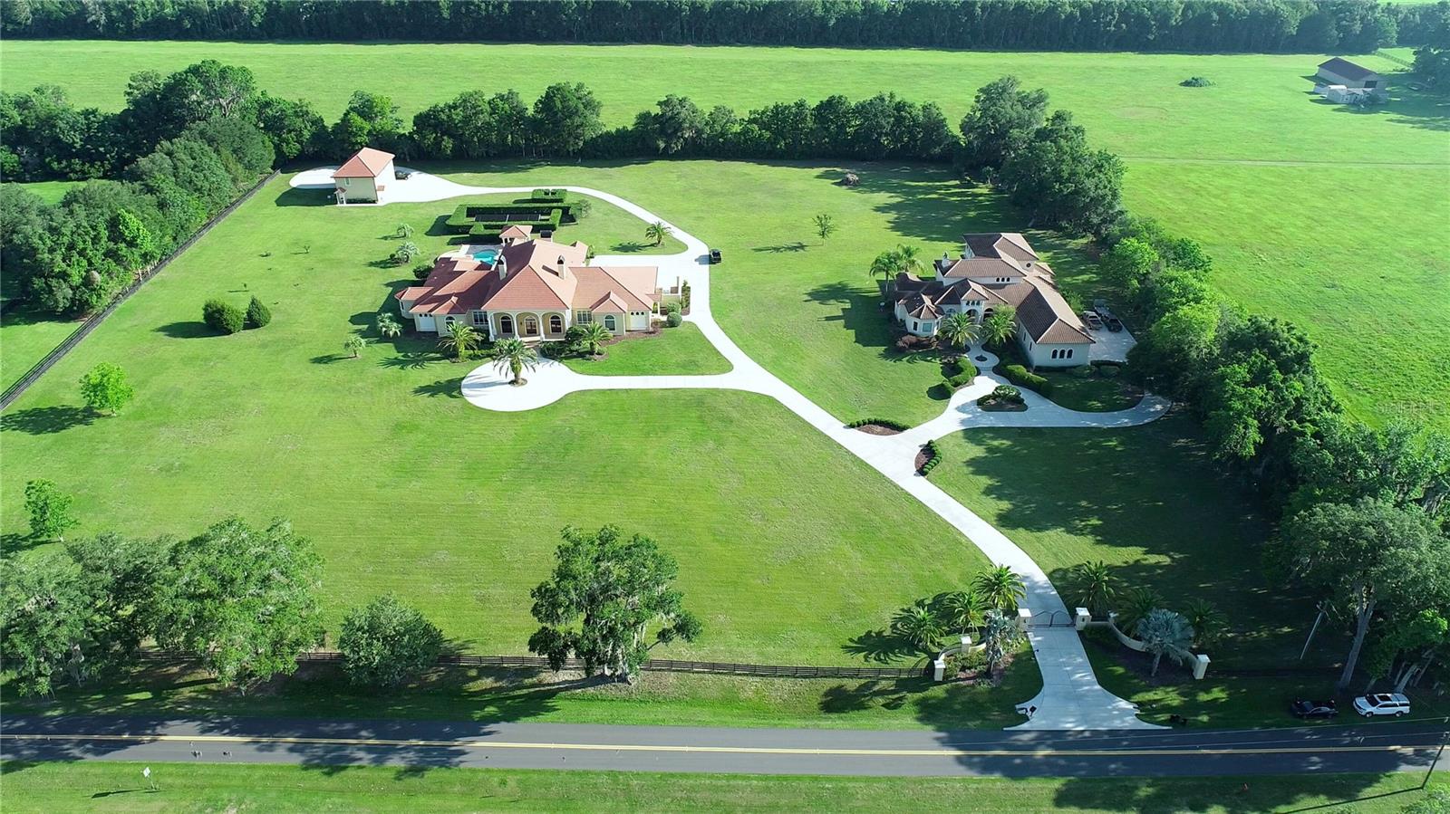 Set behind a private gate on 9+ acres sits this stunning family estate designed with style & elegance. Complete with two magnificent homes, a detached 3-car garage, and a guest home above. The first residence has 3 en-suite bedrooms, 3 full and 2 partial baths with 8,295 SF living area. Upon entering, you will be welcomed by an impressive entrance with soaring groin-vaulted ceilings & designer lighting. The 30 X 70 oversized display room with center fireplace, built-ins, & recessed lighting to display your trophies or memorabilia. Adjoining room features built-ins for displaying additional memorabilia. The spacious executive office has solid African Padauk doors, cabinets, coffered ceilings, & a generous sitting area. Bonus room is currently used as an office/copy room. Family room & kitchen area are open to formal dining room. Gourmet chef’s kitchen is outfitted with quality custom cabinetry, top-of-the-line appliances, a center island, & granite countertops; 2 raised islands on each end for extra counter space & seating. Scullery area with cabinets, microwave, oven, dishwasher, large sink, & pantry perfect for additional storage, workspace, & prep area. Primary bedroom exudes warmth & luxury with a luxurious bathroom, dual vanities, jetted tub overlooking the beautiful grounds. The level of custom finishes throughout the estate set this property apart from the competition. Swimming pool, Jacuzzi tub, plus an outdoor kitchen with a built-in BBQ ideally situated to enjoy the serene resort-style pool area. Private underground soundproof 50-foot range, barrel tile roof, and crown molding. Oversized 3 car garage with two side entry doors and half a bath. The upstairs guest house is 1,550 SF and features a 2-bedroom 1 bath with an open kitchen-living. Second residence features style, attention to detail, and masterful construction. Magnificent 2-story Mediterranean-style home with 6,402 SF of living area. Upon entering the front doors, you enter a grand living room with a 26’ ceiling and custom fireplace. 3 Sets of French Doors open to a lovely patio. Owner’s suite is off the living room, with a sitting area & dual closets. Master bath boasts double-entry walk-through style shower, garden tub, and double vanities. Marble vanity tops, shower, and bathroom floors. Large office/den with custom cabinets is just off the master. Playroom or additional office-this room could be used for many purposes (exercise, hobby, craft room, etc.). On the opposite side of the house, you will find 2 oversized bedrooms, each with walk-in closets and a private bath. Kitchen highlights beautiful custom-made wood cabinets. All appliances are stainless steel, including the 5-burner gas stove. A spacious walk-in pantry is adjacent to the kitchen, with floor-to-ceiling shelves. A wet bar with a wine fridge and ice maker is just down the hall. Nearby is the elegant dining room with a unique groin vault ceiling. A wall of French doors opens to another huge patio and drenches the family room with light. The laundry room is conveniently located next to the 3-car garage. A custom design, hand-made railing adorns the stairs. An enormous "bonus" room awaits upstairs. This room could efficiently serve as a theater, man cave, or extra private living space. There is a bar area with custom cabinets, an ice maker, and an impressive bar-style glass-door refrigerator. An inviting guest bedroom and full bath with chocolate Italian tile round out the upstairs.
