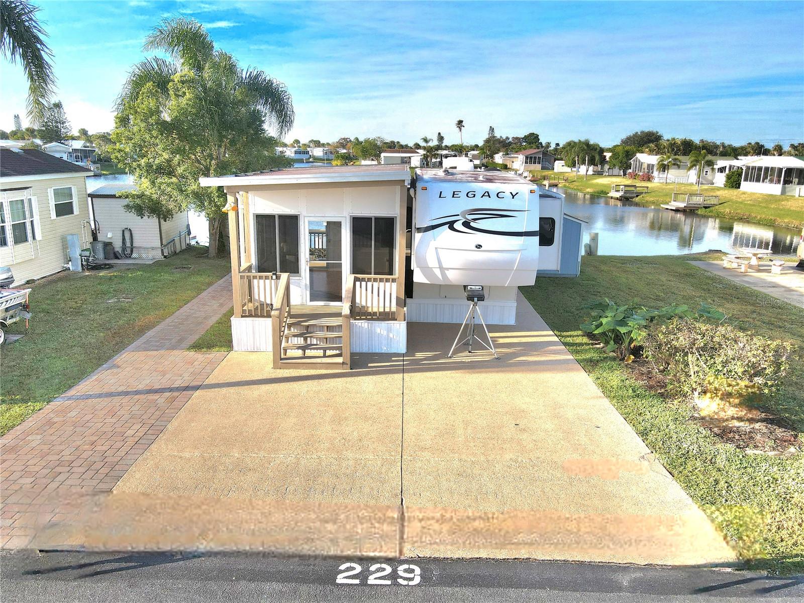 Discover luxurious living in this well-appointed 38 foot Legacy by Jayco 5th Wheel located in scenic Okeechobee, Florida. This cozy retreat features one bedroom with a California king-sized bed and modern bathroom, perfect for seasonal or comfortable year-round living. The interior showcases thoughtful amenities including an electric fireplace, gas stove, and two efficient air conditioning units.
Step outside to enjoy breathtaking western sunset views over the water from your private space. The property includes a spacious wood dock and seawall, plus an 8x10 storage shed for extra convenience. Community perks include access to a heated and chilled pool, pickleball courts, petanque, shuffleboard, and a 9-hole golf course, and catch-and-release fishing opportunities.
The well-managed Blue Cypress Golf & RV Resort HOA covers essential services including lawn care, sewer, water, and trash collection. Located near the Seminole Casino and convenient shopping options, this home offers both tranquility and accessibility. With three slide-outs and cedar closets, this property maximizes both space and storage while maintaining a comfortable living environment.
All measurements are approximate.