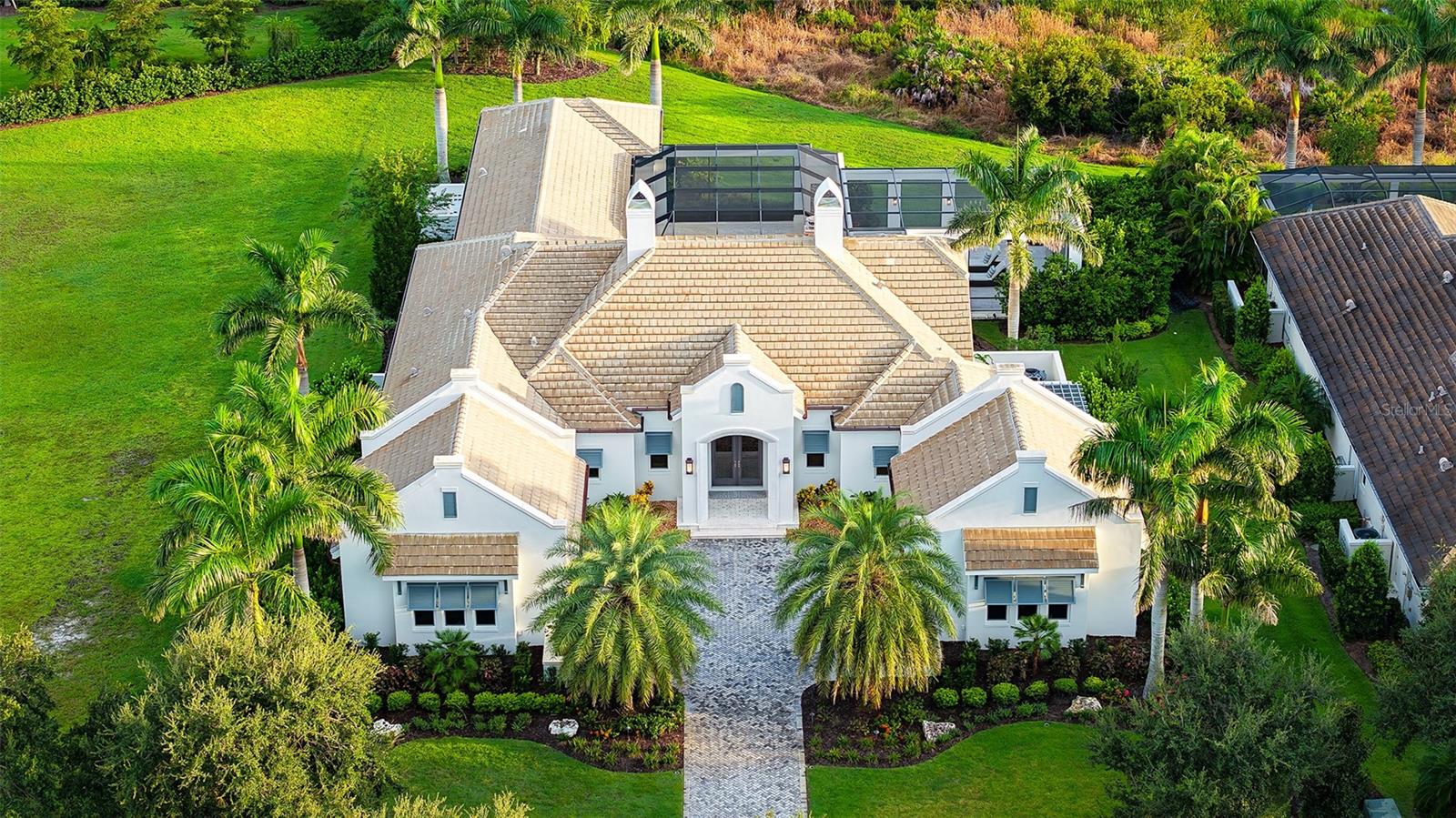 Located in the prestigious Lake Club, this stunning estate home, built with the highest level of quality by Murray Homes, features hurricane impact windows and doors and a whole-house generator for absolute comfort and peace of mind. Set on a south-facing homesite with a welcoming courtyard entry and split garages, the interior offers 3,933 sq. ft. of meticulously designed living space including 3 bedrooms in the main house, a separate guest casita, 4.5 baths, an office, and a resort-style saltwater pool and spa. The outdoor living area is designed to impress, with an expansive kitchen, gas fireplace, and detailed wood ceiling treatments. Inside, timeless design and refined craftsmanship are showcased through rich wood flooring, custom cabinetry throughout, a gas fireplace, and a versatile neutral palette. The professional-grade kitchen is appointed with top-tier appliances, a wine bar, butler’s station, and custom walk-in pantry—ideal for both daily living and elevated entertaining. The spa-inspired primary suite is a serene retreat, featuring a double vanity, oversized double walk-in closet, two additional closets, garden tub, indoor shower, private courtyard with outdoor shower, and double-glass door access to the pool and spa. Large windows allow natural light throughout the home, while dual AC’d garages for four vehicles, generous storage throughout, whole-house reverse osmosis water system, Icynene insulation, and copper gutters complete this exquisite home. This is a rare opportunity to enjoy a luxurious lifestyle in Lakewood Ranch’s most prestigious gated enclave. Residents of The Lake Club enjoy world-class amenities, including a guard-gated entrance, vibrant clubhouse, restaurant and bar, two resort pools, fitness facilities, tennis, pickle ball, fishing, and scenic trails. Ideally located in the nation’s top-selling multi-generational community, this exceptional home is just minutes from premier shopping, dining, top-rated schools, and the Gulf Coast’s pristine beaches.