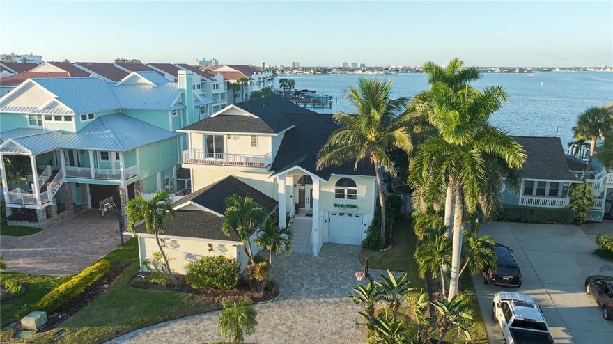 PRIVATE BEACH | WALK TO THE GULF SANDY BEACHES
This Key West–inspired Beach House on the Bay offers everything you could dream of in a Florida waterfront retreat—six balconies and patios for entertaining, panoramic water views from every room, and over 4,000 square feet of living space (5,750+ total gross area). Splash in your heated pool and spa featuring a custom dolphin inlay and cascading fountain, grill on the patio, or launch a kayak from your private dock. Surrounded by lush tropical landscaping, the property feels like a private resort. Especially rare for St. Pete Beach, this home offers both boat access and a private sandy beach—perfect for volleyball, s’mores by the fire, or building sandcastles at sunset.
Welcome to Beach House on the Bay—a rare waterfront residence offering the best of both worlds: your own private beach on Boca Ciega Bay with a boat dock and just a short walk to the white sands of the Gulf. Architecturally unique among a row of waterfront homes, this elevated five-bedroom, four-bath residence combines privacy, smart technology, and an expansive coastal lifestyle. Designed for flexible living, it features a full kitchen plus a kitchenette, two laundry rooms, and multiple gathering areas ideal for entertaining, guests, or multi-generational living.
The lower-level living area includes two bedrooms, a full bath, kitchenette, casual living and dining spaces, a second laundry room, and ample storage. Tile floors throughout, quartz countertops, and durable water-resistant wainscot finishes create a relaxed coastal feel throughout this inviting space, which opens to more than 500 square feet of covered paver patio seamlessly transitioning to the pool, spa, and private beach. A bonus room and split three-car garage complete this level.
The main level showcases soaring 14-foot ceilings, a dramatic triple-stacked fireplace, and a custom free-floating staircase. Expansive living spaces open through floor-to-ceiling glass to a 500-square-foot waterfront balcony. The chef’s kitchen features rich dark granite surfaces, stainless steel appliances, a center island, dual breakfast bars with seating for eight, and a dining area overlooking the pool and bay.
The primary suite is a true retreat with a private balcony offering breathtaking views of the pool, beach, and Boca Ciega Bay. A distinctive porthole window captures the sunrise over downtown St. Petersburg, adding a touch of nautical charm. The spa-style ensuite bath features dual vanities, granite surfaces, refined tilework, and a spacious walk-in shower. Another guest bedroom, full bathroom, and laundry room complete this floor.
Entertaining is effortless with multiple covered patios, an outdoor granite-topped bar, and generous lounge areas surrounding the heated pool and spa—all framed by vibrant tropical foliage, swaying palms, and brilliant sunsets. Smart home features enhance comfort and security throughout.
Recent updates include a 2025 roof, and the property comes fully furnished with designer décor—turnkey and ready to enjoy. Ideally located near the Don CeSar, top-rated beach restaurants, and everything St. Pete Beach has to offer, this is one of the area’s most remarkable waterfront opportunities.