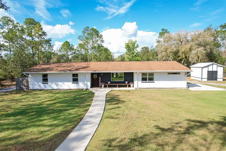 Escape to your own private country retreat on  4.5+/- acres in Eustis, where modern updates meet an exceptional outdoor lifestyle. This fully renovated block home offers 4 bedrooms, 3 full bathrooms, and thoughtful upgrades throughout, all completed during an extensive whole-home renovation in 2021.  Inside, the home features an inviting open kitchen and dining area with a beautiful real brick backsplash, real cedar floating shelves, gas cooktop (propane), and all new appliances, including a built-in convection oven, microwave and beverage refrigerator, washer, and dryer. The home showcases all new wood flooring, fresh interior paint (2023), exterior paint (2025), solid wood interior doors on the primary suite wing, custom real wood trim with crown molding, and energy-efficient LED lighting throughout.  The primary suite offers a peaceful retreat and includes a private office with its own exterior entrance, ideal for working from home or creating a flexible bonus space and could easily serve as a game room, hobby room, gym, or potential fifth bedroom.  Major infrastructure upgrades provide peace of mind and modern efficiency, including new exterior windows and doors, full home rewire, underground power to the home, new 400-amp electrical service, full plumbing repipe, new attic insulation, and two separate gas tankless water heaters. The home is serviced by a 500-gallon buried propane tank owned by the homeowner.  The main home septic system was replaced in 2022 and the second septic was added in 2025 designed for the RV and future barn bathroom.  Outdoors, the property truly shines for those seeking space, privacy, and recreation. The land features a private pond, mature trees throughout the front and back of the property, and established blueberry bushes. The front and backyard were fully fenced in 2025, offering both security and flexibility for animals or recreation.  The impressive barn/workshop built in 2021 features an insulated roof, three roll-up doors including one 12-foot door, 125-amp electrical service, and a 50-amp RV hookup and is 30 x 80 in size. An additional 12’ x 18’ storage shed built in 2025 provides even more storage space.  Additional outdoor features include a 150-yard private shooting range, hard-packed milling driveway, large concrete RV pad, detached single-car garage on slab, and a large back patio with built-in sound system, making it perfect for entertaining or relaxing while enjoying the peaceful setting.  With agricultural zoning, this property is ideal for those looking to bring horses, chickens, or other animals, while still enjoying the comfort and efficiency of a beautifully updated home.  This rare property offers the perfect balance of privacy, functionality, and modern upgrades all just a short drive from town while feeling worlds away.