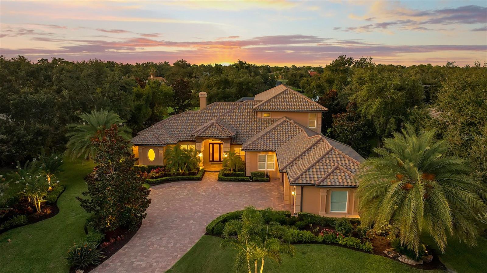 Welcome to your dream home, a sanctuary of elegance and comfort nestled on an exclusive, private street with only nine residences and no neighbors across the way—just the tranquility of a natural preserve. This remarkable property in The Oaks Clubside, with 4 bedrooms, 5 full bathrooms, and 2 half baths, boasts impact windows and doors throughout, providing peace of mind and a quiet, secure environment. Step inside to discover an open floor plan adorned with a blend of rich wood and luxurious travertine floors. Each of the large bedrooms is an en suite retreat, offering privacy and comfort for residents and guests alike. On the first floor you will find a huge master suite, with his-and-her closets, and a luxurious master bathroom that has two separate vanities, a walk-in shower and soaking tub. The two additional bedrooms are generously sized. The open kitchen features cherry wood cabinets, a granite island and high end stainless steel appliances. The breakfast nook is flooded with natural light and offers a lovely view over the pool. The second story has a fourth en-suite bedroom, and balcony overlooking the golf course and lake. And, for those who love to entertain, the game and media room is designed for fun gatherings of friends. The heart of the home extends outdoors, where you will find an impressive outdoor kitchen area perfect for grilling and dining alfresco. Enjoy a beautiful, long view of the Heron #14 and the serene lake beyond—a panoramic scene that will take your breath away every day. This home is loaded with thoughtful additions, including three new exterior ceiling fans for comfort on warm days, custom office closet shelving and a secure dog run fence for your furry friends. The garage boasts a durable epoxy floor and hurricane-rated doors. Additional upgrades abound with 4 new AC units with UV lights for optimal air quality, a new roof, two-stage pool pump and new irrigation pump, new tankless Navian water heater to name a few. You absolutely must see this home to appreciate all it has to offer. Membership in The Oaks Club, Sarasota’s premier golf and country club is required with home ownership.