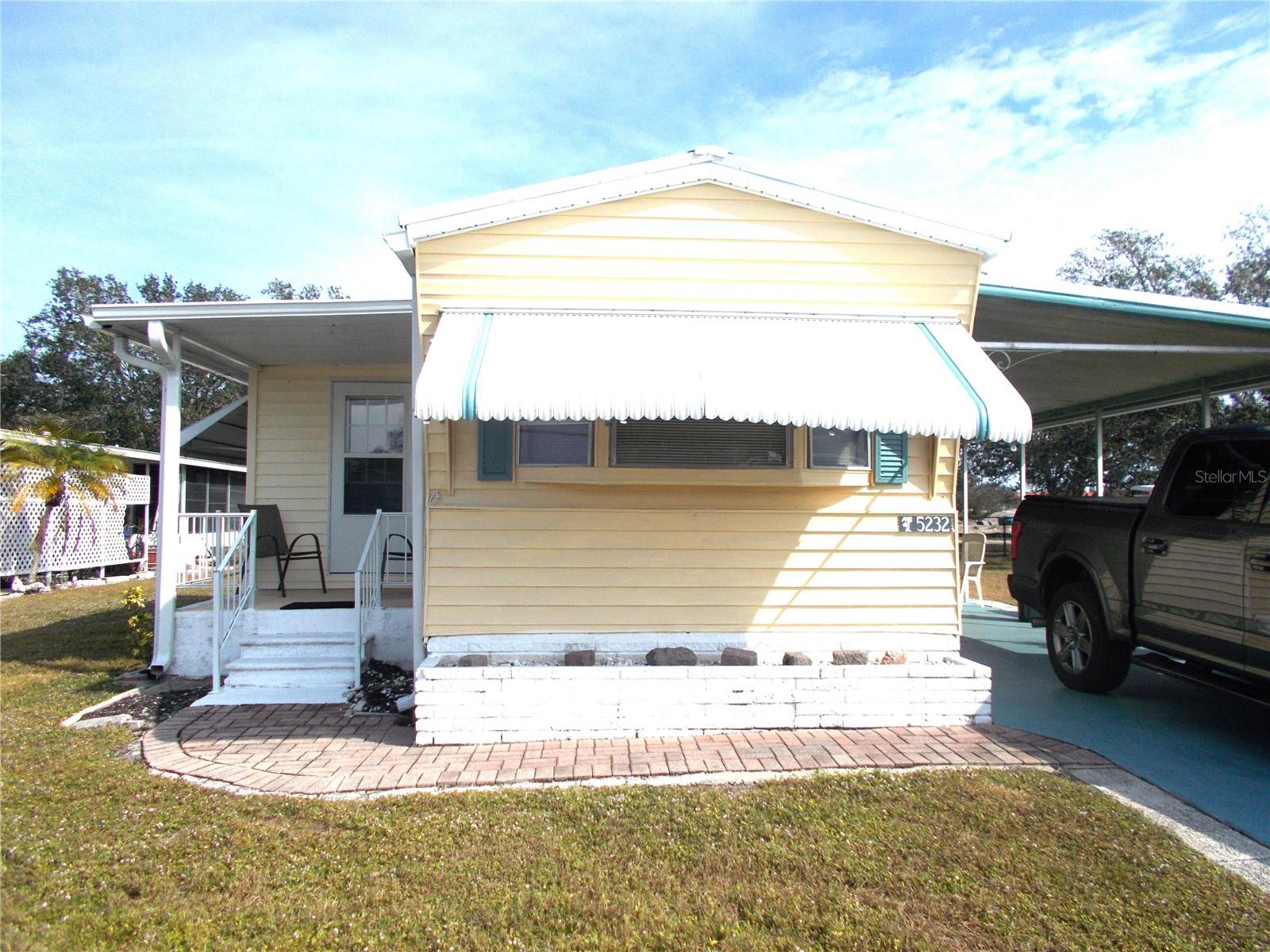This is a 2 bedroom, 2 bath furnished home with bump outs, NOT IN THE PET SECTION. Bump out in the Living Room allows space for a Dining Room table. It has a split floorplan with Primary Bedroom in the back of the home. This bedroom also has an 8 X 9 bump out which can be used as an office or for extra storage. As per owner, new membrane roof in 2023, new vapor barrier installed in 2022, new AC with duct work installed in 12/22 and new Hot Water heater 3/23. Sewer drain was replaced from house to street in 1/22 as well as 4 new windows in the back room. Washer and dryer are located in the shed and the trees in the backyard give it a park feeling. You also have a lovely porch off of the living room where you can sit and relax. In Holiday Park you own the land with a deed and your $195.00 monthly maintenance fee ($2340.00 a year) is included in your taxes. The community features 2 clubhouses, 2 swimming pools, a library, a fitness room, tennis courts, pickleball & bocce courts, to name a few. You are close to shopping, dining, entertainment, numerous golf courses, sports facilities, and SW Florida's renowned beaches. Come take a look!