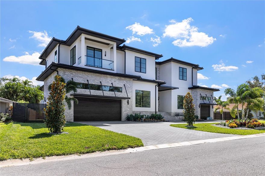 Step into elevated luxury living with this stunning 5-bedroom, 6.5-bath custom estate built for an executive family, featuring 12' ceilings on the first floor, 10' ceilings on the second, and a grand luxury design across over 5,483 sq ft of impeccably crafted living space. A dramatic 22-foot entry with overhead skybridge, oversized windows, and custom iron doors welcomes you, complemented by four Palecek Corsica pendant lights, backlit LED mini-tray grid, and marble-tiled bench area, creating a first impression that is truly unforgettable. Signature design elements, including custom decorative walls and high-end finishes throughout, set the tone for sophisticated living.

The heart of the home is a gourmet kitchen showcase, complete with Wolf SubZero appliance package, built-in coffee maker, wall double oven with Wolf's convection system, custom hood, and a quartz waterfall island with integrated sitting area and oversized sink. Luxury skinny shaker cabinets (Waypoint Maple Almond) provide durable, elegant storage, while a butler's pantry includes an additional full-size refrigerator and wine cooler. A custom wine cabinet is seamlessly integrated into the dining room for effortless entertaining.

The great room living space features soaring 14' ceilings, a custom built-in fireplace with fluted wood and large-format porcelain tile surround, and expansive sliders opening to the pool and outdoor entertaining areas. The executive study dazzles with water views, full-wall built-ins, and Arhaus Bronze Arrow accents, while the powder and pool baths are adorned with leathered porcelain, marble mosaic, oversized quartz countertops, and unique design elements for a refined experience.

The luxurious owner's suite offers a sitting area with linear fireplace and water views, a spa-inspired bathroom with dual rain shower heads, floating cabinets, 6cm quartz countertops, and oversized linen closet. The master closet includes a full shelving system, island, and bench for seamless organization. Additional bedrooms and an oversized game room provide space for family and guests alike.

Step outside to a resort-style backyard featuring a large, heated pool and spa with spillover waterfall, integration of foxtails, and upgraded outdoor kitchen by Artisan. The over 15,000 sq ft estate lot provides privacy and grandeur, with a metal and stained wood fence, lush landscape package, planters, salt-and-pepper granite accents, and ambient lighting. Outdoor living spaces include pool baths, frosted-glass doors for easy lanai access, and multiple entertaining zones for family and guests.

Smart-home amenities include a Generac whole-home generator, hurricane-rated casement windows throughout, and pre-wired EV chargers. The oversized circular paver driveway with split 3-car garage completes the estate's convenience and luxury. Every detail, from high-end finishes to thoughtful living spaces, is designed for comfort, style, and sophisticated Florida living.