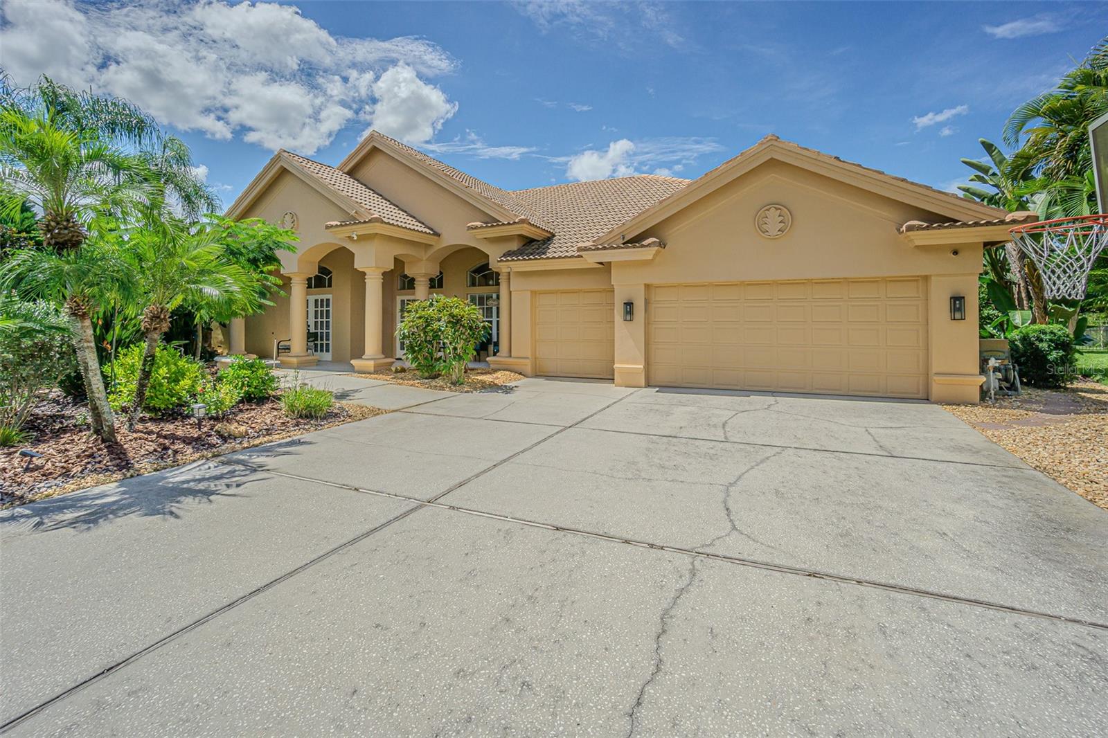 Nestled on the shores of Lake Tarpon in the desirable community of Juniper Bay, this exquisite residence offers the perfect balance of privacy, natural beauty, and refined living. Situated on a premium .72-acre pond and conservation lot at the end of a quiet cul-de-sac, the property provides serene surroundings with no rear neighbors. From nearly every room, enjoy sweeping views of the pool, mature gardens, and conservation area, where deer and a variety of birds are daily visitors. This thoughtfully designed 5-bedroom, 3-bath, 3-car garage home features a versatile triple split floor plan that ensures both privacy and functionality. As you enter through the elegant glass double doors, you are welcomed into a formal living and dining area with soaring ceilings adorned with crown molding. Ceramic tile flooring flows throughout the main living areas, adding both style and durability. The primary suite is a true retreat, complete with tray ceilings, crown molding, dual vanities, a soaking tub, a private water closet, and two walk-in closets for unparalleled storage. Adjacent to the suite, the fifth bedroom—perfect as an office—features double doors, Brazilian oak flooring, and its own closet. Two guest bedrooms are generously sized and include charming window seats. The back bedroom doubles as a private en-suite when paired with the pool bath. At the heart of the home, the gourmet kitchen boasts white cabinetry, double ovens, granite countertops, 42-inch upper cabinets with crown molding and under-cabinet lighting, a decorative tile backsplash, stainless steel appliances, and an extended island ideal for entertaining. The adjoining family room offers warmth and character with its natural wood-burning fireplace framed by coral surround and built-in shelving. Step outside to your own private oasis. The spectacular pool area with a sheer descent waterfall creates a tranquil backdrop for relaxation, while the expansive deck provides plenty of space for outdoor dining and entertaining. A fenced yard adds security and peace of mind for pets and family. Additional highlights include: Abundant natural light through extensive windows and French doors, laundry room with built-in cabinetry and utility sink, and expansive pool and conservation views from nearly every living space. As part of the Lansbrook community, residents enjoy exclusive access to Lake Tarpon via a fishing pier and boat ramp, as well as two parks with playgrounds, basketball, pickleball, and a party pavilion. The community also offers a golf course, and direct access to the Pinellas Trail for walking, jogging, and biking. Top-rated schools add to the appeal of this highly desirable location. This exceptional home offers not only a stunning property but also a lifestyle defined by nature, recreation, and convenience.