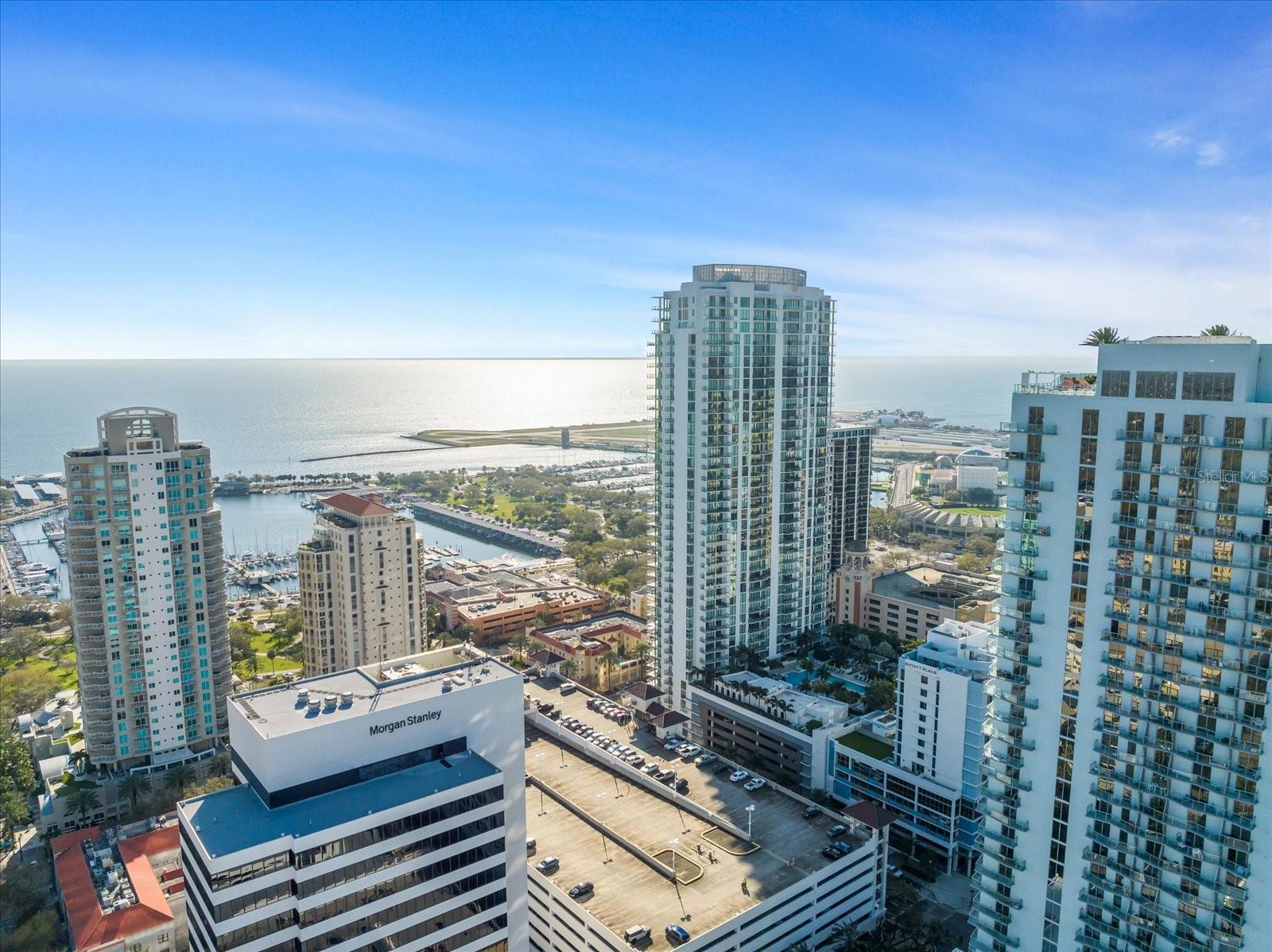 Welcome to an unparalleled urban retreat, a chic and modern 2-bedroom, 2.5-bathroom residence with a den, spanning an impressive 1894 sq ft, with an XL 400 sf terrace, in the very heart of vibrant St. Petersburg. This luxurious home is perfectly positioned in the center of downtown, placing you just steps away from the very best of Tampa Bay. You will be immersed in a world of acclaimed restaurants, the beautiful 7 mile long waterfront park system, renowned museums, eclectic art galleries, and charming coffee shops, with the vibrant parades and festivals on the St. Pete Pier right at your doorstep.
Step inside to be greeted by breathtaking water views that set the tone for this upscale home. The open layout is adorned with sleek finishes and flooded with natural light, creating an inviting ambiance. The residence features a massive terrace off the southeast end of the building, offering spectacular views over Tampa Bay and all the iconic sites of downtown St. Pete. Additionally, the primary bedroom boasts a private terrace, perfect for morning coffee or an evening glass of wine while watching the sunset over the bay.
Designed for the modern urbanite, this home includes two balconies, an in-unit washer/dryer in separate laundry room, and a flexible den/office space. Enjoy the ultimate convenience of assigned parking with a garage entrance on the same floor as your residence, placing your parking spots directly by your door. Elevator access leads you to a suite of building amenities, including a game room, gym, and spa. Soak up the Florida sun by the pool or on downtowns best pool deck, and for entertaining, the cabana provides an ideal spot for hosting gatherings. The amenity floor includes a clubroom for all your gatherings that can be reserved for private parties and boasts views over the bay to watch sunrises and the fireworks over the pier. The game room has a pool and ping pong table for fun with friends. The 3000sf fitness center has all the weight and cardio machines you could wish for and a separate studio for spin and classes where you can bring your personal trainer for a private session. This property offers a perfect blend of sophisticated urban living and resort-style amenities, making it an ideal oasis in the heart of it all.