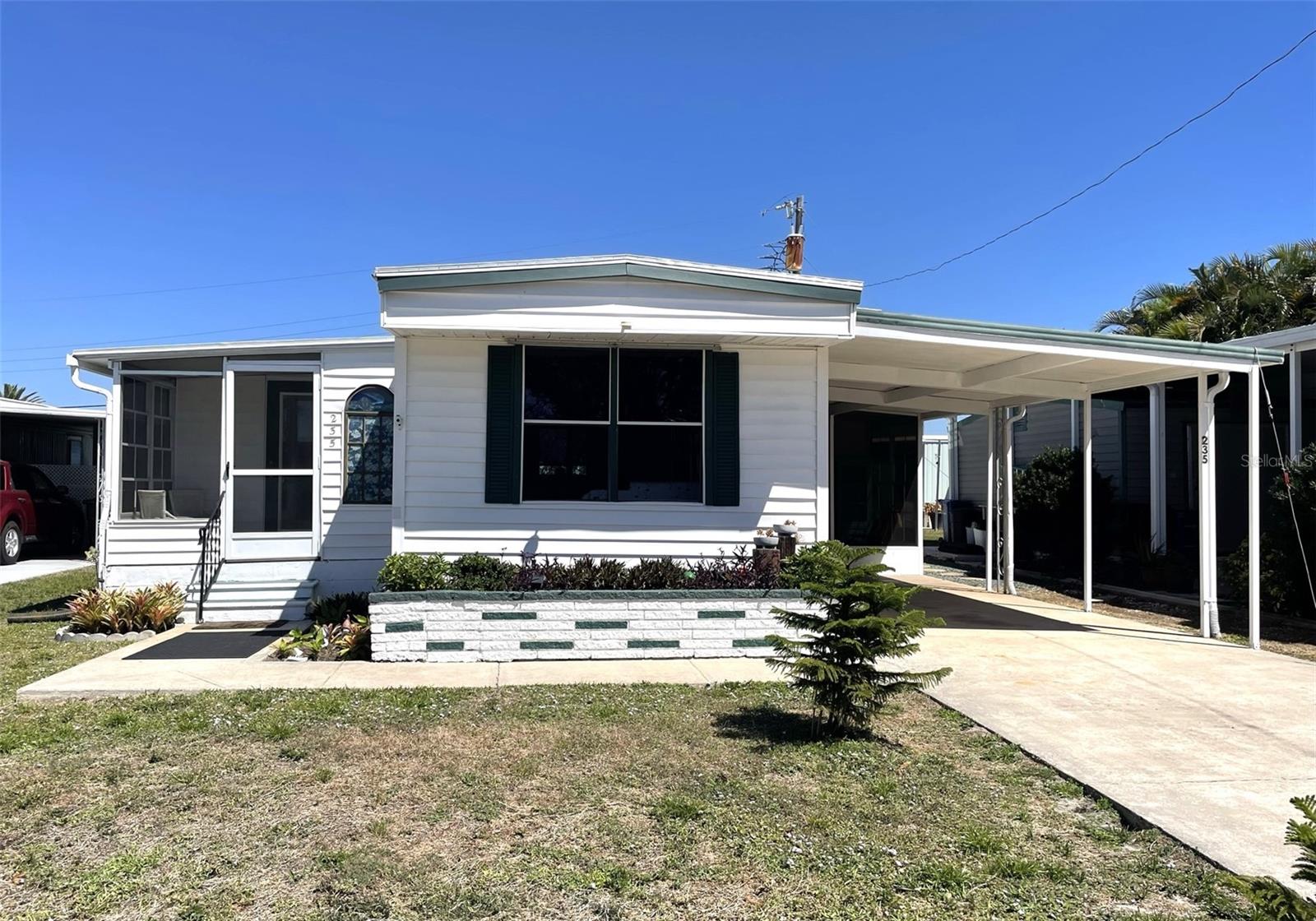 Nestled in the highly sought-after boating community of Harbor Cove, this unique and lovely manufactured home offers an impressive 1,129 sq. ft. of living space, thanks to two thoughtfully designed additions. Boasting a wide-open floor plan, the home’s kitchen seamlessly connects to the spacious living room and sun-filled dining room, where large picture windows flood the space with natural light. Just off the dining room, a charming Florida room provides the perfect spot to enjoy Florida’s mild winters. To the right of the home, a versatile addition houses a home office with laundry facilities and a bonus room ideal for crafting or hobbies. The split-bedroom layout ensures privacy, featuring two master suites—one at each end of the home. The home can comfortably sleep 7 adults. Outside, the beautifully landscaped lot is enhanced by a picturesque concrete mosaic table and benches, perfectly positioned to enjoy the serene view of the neighboring garden. A new 10' x 8' shed with a workbench offers additional storage and workspace. The home has been lovingly maintained, with a freshly painted exterior and a durable 2015 membrane roof. Turnkey furnished with an HOA of only $99 per year, this home is immaculate and ready for its next owner. Harbor Cove is a premier 55+ waterfront community known for its active lifestyle, fantastic boating access, and resort-style amenities. Residents enjoy direct access to the Myakka River, a marina and boat ramp, heated pools, a clubhouse with year-round activities, tennis and pickleball courts, and so much more. Whether you're looking for a place to dock your boat or simply relax in a vibrant social setting, Harbor Cove offers the perfect Florida lifestyle. Don't miss this rare opportunity to own a one-of-a-kind home in this highly desirable community!