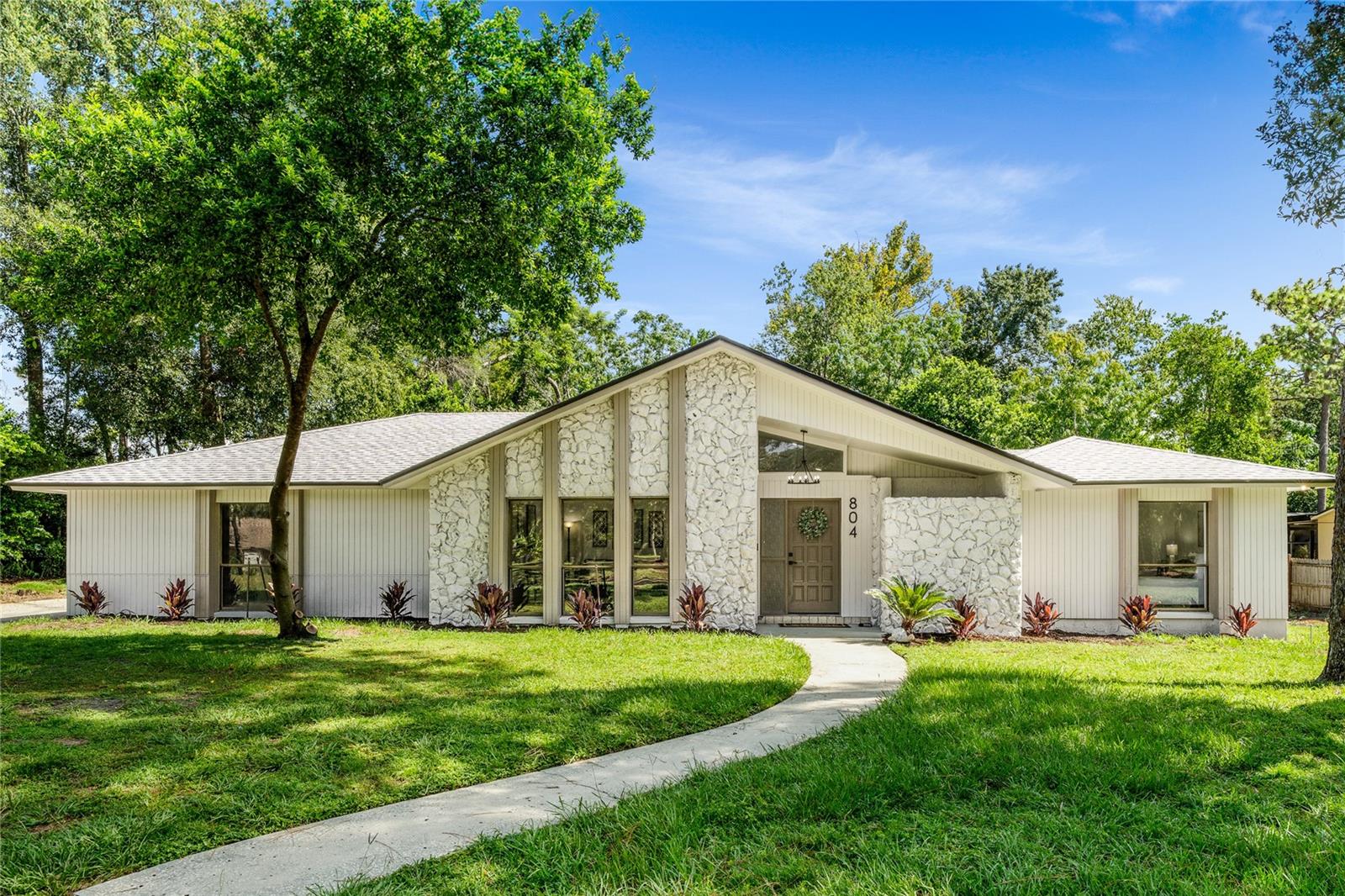 Beautifully RENOVATED 4-BED / 2.5-BATH home nestled in the heart of SWEETWATER OAKS. Exquisite remodel choices and attention to detail bring modern living appeal to this classic block constructed Longwood home. The exterior features a NATURAL FIELDSTONE facade and earth-tone color pallet plus a cozy covered entry. Warm-tone LUXUARY VINYL PLANK flooring with a “farmhouse” feel runs through every room.
The kitchen was re-imagined and expanded to become what every modern chef desires. TWO-TONE CABINETRY with 42” uppers capped with crown molding, QUARTZ counters, peninsula bar, Whirlpool stainless appliance package, longneck faucet and stylish MATTE BLACK enhance this enlarged space. The volume ceiling of the living spaces accentuated by an ORIGINAL WOOD BEAM add to the authentic ambiance of the home. Double slider doors open to a LARGE COVERED LANI, oversized paver swimming pool deck with a freshly screened pool cage offering views of a private backyard. Redesigned FIREPLACE brings a modern flare to the dining room. Two and a half fully-remodeled bathrooms were designed for luxurious and private experience.
MECHANICAL UPDATING INCLUDES: ROOF (2024), CARRIER HVAC (2025), HOTWATER HEATER (2025).
Residents of Sweetwater Oaks enjoy the benefits of the Lake Brantley High School district (Sabal Point Elementary & Rock Lake MS), use of Sweetwater Beach & Boat Ramp on Lake Brantley and access to the Wekiva River. Riverbend Park offers complete amenities for an active lifestyle: Tennis Courts, Pickleball, Basketball, Softball, Scenic Nature Trails, Kayak/Canoe and much more. This is a rare opportunity, not to be missed!!