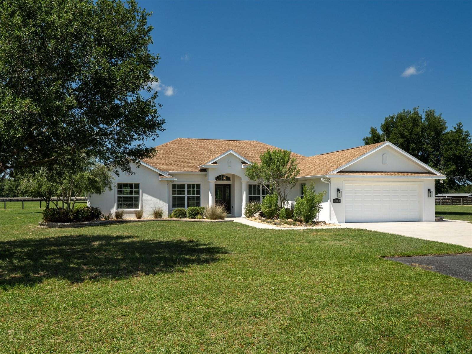 Located just 8 minutes from the World Equestrian Center and 10 minutes from HITS, this fully fenced 22.44-acre farm in Ocala offers a blend of comfort, functionality, and convenience. The 3-bedroom, 2-bath home offers an open floor plan and high tray ceilings throughout the main living areas. A screened-in back patio offers a relaxing space to enjoy the outdoors, while the beautifully paved driveway provides ample parking and leads to a spacious 2-car garage. A waterfall feature in the front garden adds a distinctive and welcoming touch to the property. The block barn on the property includes 12 stalls with excellent ventilation, a tack room, two wash/groom stalls, and a laundry room, providing all the essentials for horse care. A comfortable office and kitchenette make managing operations easy, and the barn also includes 1.5 bathrooms for added convenience. The property includes a 100x200 synthetic surface arena with a concrete border and irrigation, providing a perfect setting for training. Whether you're a competitive rider, trainer, or equestrian enthusiast, this property offers everything you need for success, making it an outstanding opportunity to own a premier piece of Ocala’s equestrian scene!