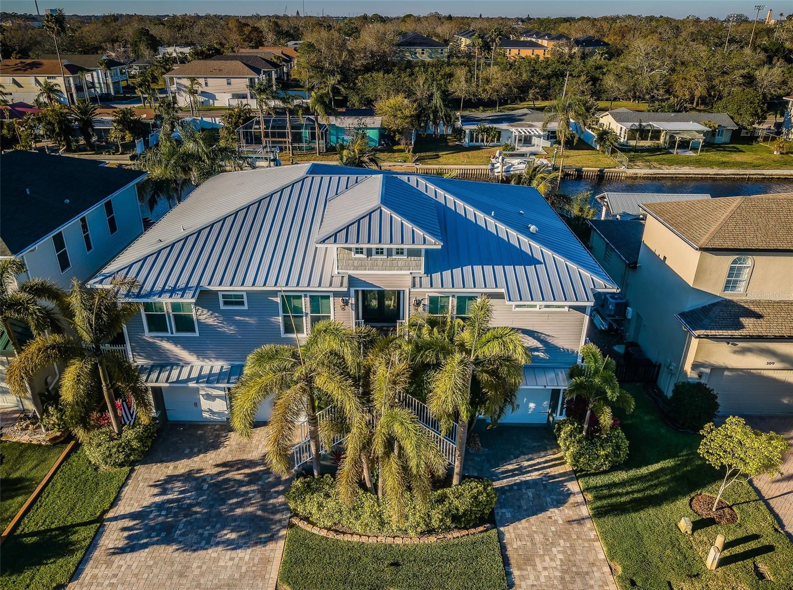 Exquisite Waterfront Living in Ultimate Luxury! Experience unparalleled elegance in this extraordinary Tarpon Springs estate, designed for those seeking the highest standard of living. Stunning curb appeal, a spectacular pavered drive, and a grand entrance welcome you into one of Tarpon Springs’ finest residences. Throughout its spectacular 4 bedrooms, 3 baths, and 3 car garage, 10-foot ceilings, 8-foot interior doors, wainscoting, arched doorways, 5 1/2-inch baseboards, crown molding, and granite finishes shine. While the formal dining room boasts a tray ceiling and ample room to host sit down dinners, the gorgeous great room is appointed with a fireplace and contemporary hearth along with multiple sliders introducing the covered waterfront balcony; further expanding your entertainment venue. Speaking of which, the adjacent chef’s kitchen is worthy of its own magazine layout. Including a butler’s pantry, the huge, granite island offers ample space for both casual dining and displaying party platters. Bold pendant fixtures and recessed lighting illuminate the splendor of this space bookended by a storage pantry and a breakfast room framed by two picture windows. Custom features include upgraded cabinets with soft close drawers, under island cabinets and drawers for additional storage, KitchenAid appliances, double ovens (both convection), and an induction glass top crowned with a pot filler and decorative hood. As for the master suite, it is awash with sunshine that reflects off the tray ceiling and is accompanied by the en suite bath that shows like a fine hotel’s retreat. From the frameless glass doors of the indulgent shower room to the granite-topped counters and rich cabinetry, this oasis is picture perfect. The other two baths were treated to the same premium fixtures and finishes. On the lower level, the open-air lanai is magnificent, spacious enough for any furniture configuration and as an alfresco dining destination. There’s also an expansive side patio serving as the ideal spot for taking in the sun, lounging in the hot tub, or enjoying a cozy fire pit on those refreshing fall and winter evenings. Lush grass edged with decorative stone and slate form a charming pathway leading to the pavered walk and seawall completed in 2015. Panoramic water views include the 280 sf dock and two boat lifts (12,000 lb. and 2,500 lb. Davit Masters) with direct drive motors. In addition to the home’s raised construction, beneath a standing, seam metal roof, a Trane A/C unit, lcynene insulation, and a central vacuum system are installed besides PGT hurricane-impact, insulated windows, and pocket sliders. Reclaimed water cycles through a Rainbird sprinkler system. The 3 garage boasts 2300 ft and 8-foot doors with their own battery backup. Beyond this uniquely designed manse, you’re surrounded by the absolute beauty of Tarpon Springs. Famed for its historic sponge docks, it’s a 5-minute walk to downtown’s eclectic shops and dining; a less than 5-minute ride to Sunset Beach and Fred Howard Park; a 20-minute boat ride to the magnificent Gulf of Mexico that leads to Anclote Key, Three Rooker Island, and Honeymoon Island; and a bit farther south to the world-famous Clearwater Beach. Just a short distance from Delightful Dunedin, the multi-purpose Pinellas Trail, and only 40 minutes to Tampa International Airport. A golf cart friendly community with an annual HOA fee of $500, this home offers an unparalleled lifestyle; the pinnacle of waterfront luxury