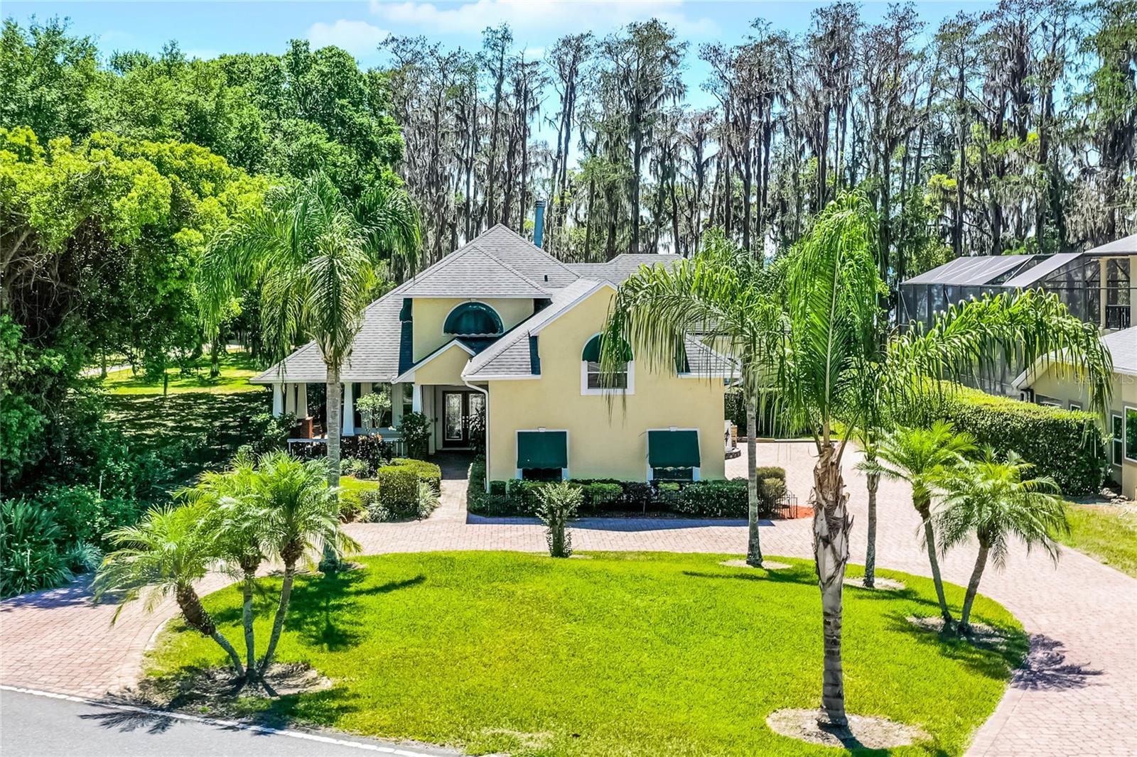 One or more photo(s) has been virtually staged. Lakefront paradise on the Clermont Chain of Lakes! Indulge in the ultimate Florida lifestyle with this spectacular four-bedroom waterfront estate directly on Lake Louisa, offering unparalleled access to the pristine Clermont Chain of Lakes. This extraordinary property seamlessly blends luxury living with the natural beauty of lakefront recreation. Step inside to soaring 18-foot ceilings and elegant travertine floors throughout. The open floor plan captures breathtaking lake views from nearly every room. The primary suite features a tray ceiling, expansive California 13-by-12-foot walk-in closet, and spa-like bath complete with garden tub and separate shower. Three-car garage plus extra space for additional parking, and a circular drive. No HOA! If you don't need the fourth bedroom, it is a great place to entertain in style as a versatile bonus room upstairs, ideal for a home theater, game room or additional living space. Outside, the resort-style pool and spa offer the ideal vantage point to witness spectacular sunsets over the water as well from the 38-by-34-foot screened porch. The park-like backyard showcases meticulous landscaping with brick-paved walkways leading to your private dock with covered boat lift and deck. Whether you're kayaking at dawn, wakeboarding in the afternoon, fishing for dinner, or simply cruising the chain on your pontoon boat, the water adventures are endless. Enjoy the convenience of waterfront dining at several restaurants accessible by boat, or venture into downtown Clermont for boutique shopping, diverse dining options, local breweries and community events. This prime location offers the serenity of lakeside living while remaining just a short drive from Orlando International Airport and world-famous attractions including Walt Disney World. This rare offering combines luxury, recreation and location in one spectacular lakefront package, where every day feels like vacation. Please see the interior/drone video and then make your appointment!