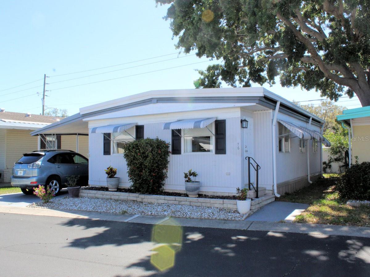 Palm Hill County Club, a popular 55+ community, is where you will find this nicely updated two bedroom, two bath manufactured home. This home really shines; furnishings stay making for an easy move right in. Your furry friend (20 lbs) is also welcome. You’ll love the community. From pools, pickleball, tennis, golf, shuffleboard, bocce ball to entertainment at the two clubhouses there is something for everyone. The monthly fee of $677 includes essential services like water, sewer, garbage and recycle pick-up, lawn care, cable and internet. This manufactured home is ready for new owners. Floors are updated with easy to clean luxury vinyl flooring. Walls are painted with neutral color. The baseboard provides an appealing finish to the contemporary look. The upscale furniture will stay for the new owners. Newer six paneled doors throughout provide a polished look. Step up into the separate kitchen from the comfortable Florida Room. The workspace is well configured with a cozy built-in nook for quick lunches, range, and overhead microwave on one side and cabinets, generous counter space, refrigerator and double sink on the other side. There is a natural flow from the kitchen into the main living area. The established dining space is on one end. Behind the table built-in storage provides the optimal space for storage while the cabinets above are ideal for displaying special items. The remaining area is the comfortable living room. The updated exterior door at one end, a modern fireplace, and crisp curtains add to the ambiance. The two bedrooms lie at the other end of the home. The primary has a walk-in closet, and an updated electric box. The ensuite bath has shower, newer vanity, sink and toilet. The smaller guest bedroom has plenty of space in a wall closet. The second bath has lots of counter space on the updated vanity and a tub with shower. All that is needed is to bring your personal items. The home had a roof over completed in 2023 with a warranty for the new buyer. Another plus is the vapor barrier has been completely replaced. Off the carport there is a bonus Florida Room- The utility shed with washer and dryer is behind a door in the Florida Room. There is no need to go outside for laundry chores. In addition, a door in the back leads outside to a cozy patio. A share of $35,000 in the community is included in the reasonable price of this spotless mobile home.