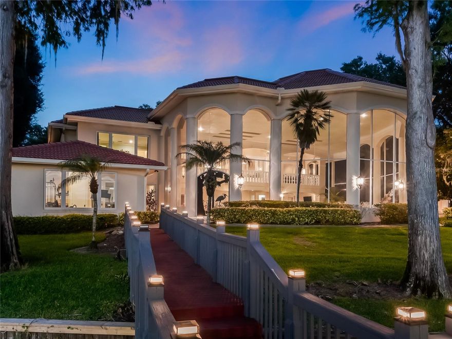 This luxurious 5-bedroom lakefront home with over 7000 square feet offers a full view of Lake Butler within the exclusive Isleworth Golf Community and Country Club. This amazing premium homesite offers unparalleled full sunset views with a sandy beach and well-maintained clear waterfront with a seawall. Upon entering the home you are welcomed by a grand foyer boasting soaring ceilings, intricate moldings, and stunning crystal chandeliers. The open floor plan seamlessly connects the formal living spaces, creating a sense of flow and spaciousness. Expansive windows throughout allow for an abundance of natural light, offering breathtaking views of Lake Butler and surrounding greenery. The gourmet kitchen is a chef's dream, featuring top-of-the-line Thermador appliances, custom cabinetry, and a large center island. It seamlessly transitions into the family room, creating a perfect space for entertaining guests or spending quality time with family and friends. The formal dining room also provides an elegant setting for dinner parties. All doors lead out to the balcony offering a serene escape to enjoy picturesque sunsets while entertaining guests. A few of the other exceptional features of this home equipped with a backup generator include an office, gym, and a secondary full kitchen and laundry room perfect for multi-generational families or houseguests. Stepping outside, the backyard is an oasis of relaxation and entertainment. The expansive outdoor living space includes a covered screened patio, an outdoor kitchen, a pool, a waterfall, and a spa, all overlooking the pristine lake. A private boat dock allows easy access to the Butler Chain of Lakes, providing endless boating, fishing, and water sports opportunities. This beautiful home truly offers a one-of-a-kind Florida lifestyle, combining the beauty of nature with the utmost elegance and sophistication.