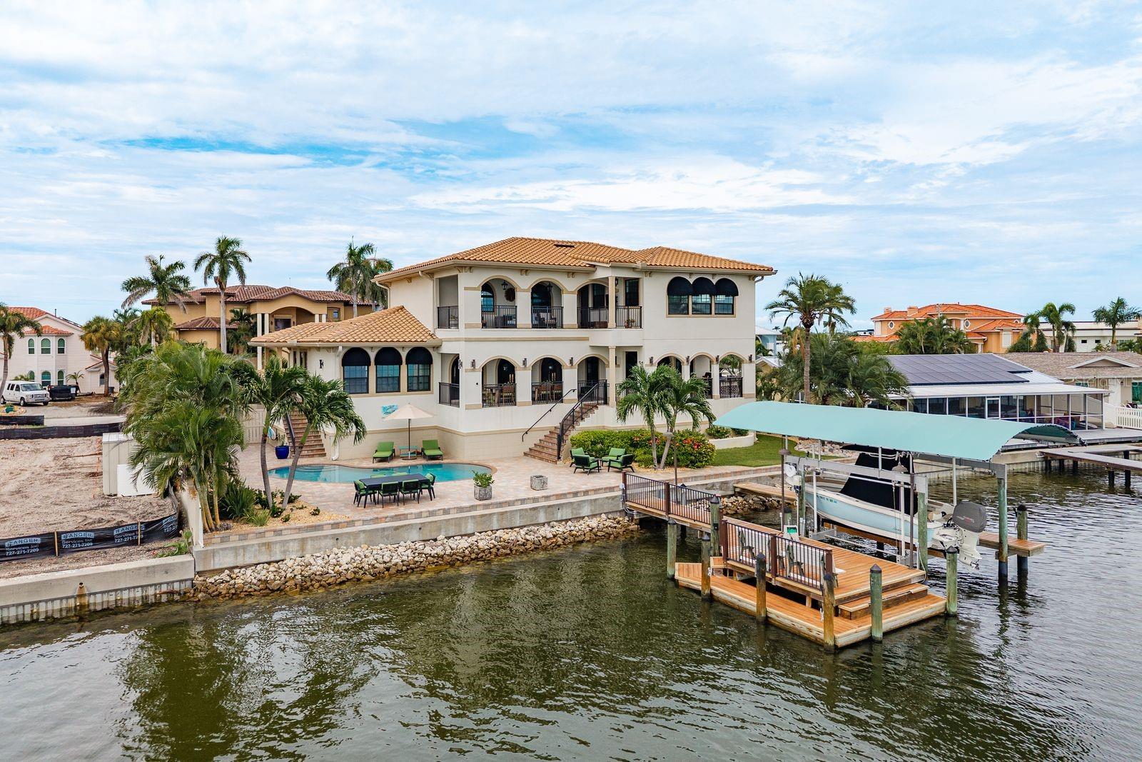 Welcome to an extraordinary waterfront lifestyle in the exclusive Yacht Club Estates, where every detail is designed to inspire both comfort and prestige. This 3-bedroom, 3-bath, 3,600+ sq. ft. residence sits on a rare cul-de-sac lot with 100 feet of prime WATERFRONT, a custom dock with 32’ lift, water, electric and solar lighting, plus a new (2019) seawall for lasting peace of mind. Built with enduring strength, the home features reinforced 2x6 insulated walls, impact windows, city gas, and an elevated design that kept the main living areas untouched through recent hurricanes, only the garage was affected. Enter through custom Monarch iron doors into a grand foyer with sweeping staircase and bespoke railings, leading to open living and dining spaces that flow effortlessly to a waterfront terrace for unforgettable entertaining. The chef’s kitchen boasts Viking appliances, quartzite countertops, wine cooler and icemaker, while the entire upper level is reserved for the owner’s private retreat, complete with balcony, dual closets, and a spa-inspired bath that feels like your own sanctuary. Two guest bedrooms, a dedicated office, heated saltwater pool, and dual 2-car garages create flexibility for every lifestyle. With direct access to Boca Ciega Bay, the Gulf, and St. Petersburg’s world-class beaches and downtown, this home offers more than luxury, it delivers a feeling of escape, sophistication, and the ultimate Florida lifestyle. Homes of this caliber in Yacht Club Estates are rare and highly sought after, schedule your private tour today before this opportunity is gone.