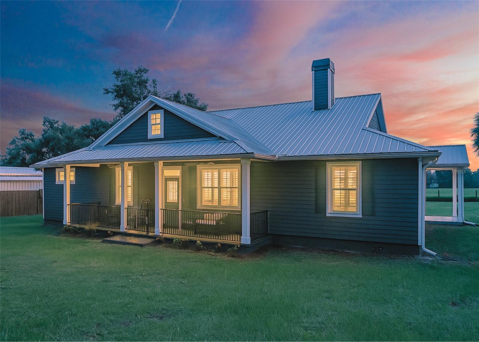 Country dreams really do come true with this incredible North Dade City estate! Set on just over 5 acres, with the option to purchase an additional adjoining 5 acres, this 3 bedroom, 2.5 bath home comes complete with a massive nearly 2,000 sq ft drive-through barn, above-ground pool, and all the charm you’ve been waiting for. Built in 2018, it still feels like new with no detail overlooked. Shady trees frame the property, which also features a separately fenced pasture, front and back covered porches, and a 1-car carport for easy unloading. Inside, a sweeping open floor plan welcomes you with tile flooring throughout, crown molding, wainscoting, upgraded lighting, and thoughtful design touches at every turn. The living room centers around a brick-accented fireplace and flows seamlessly to the dining room and stunning chef’s kitchen. Granite countertops, a breakfast bar, recessed lighting, and matte finish appliances make it a beautiful and functional space for everyday cooking or entertaining. A convenient half bath opens to the back porch and pool area, while an oversized laundry room with cabinets and granite counters adds extra practicality. The primary suite is a true retreat, with French doors to the back porch, his and hers closets, and a luxurious ensuite bathroom featuring a clawfoot soaking tub under a chandelier, dual sinks, a private water closet, and a large walk-in shower. On the opposite side of the home, two generously sized bedrooms share a full Jack-and-Jill bathroom. Bring your animals and toys, this property is ready for it all! The barn offers 2 well-kept stalls with water and electric, plenty of storage, and even twinkle lights overhead for added charm. Whether you’re enjoying the peaceful views, relaxing poolside, or exploring nearby downtown Dade City’s shops, eateries, and events, this property delivers it all. Don’t miss your chance to own it, call us today!
