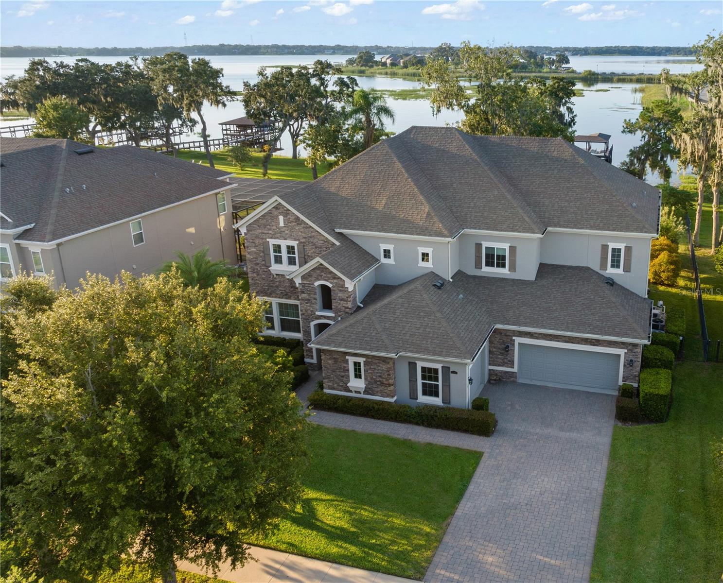 Experience breathtaking lakefront living in this exceptional estate home with a private dock in one of Winter Garden’s most sought-after gated communities: Hickory Hammock at Johns Lake. Perfectly positioned on the shores of Johns Lake, this spacious 5-bedroom, 4 full-bath, 2 half-bath residence offers the ideal combination of elegance, comfort, and outdoor adventure. Whether unwinding on the dock at sunset, setting out for a day of boating and fishing, or simply enjoying the serenity of the water from the private backyard, this home provides a rare opportunity to embrace the Florida lifestyle. Designed for both entertaining and everyday living, the thoughtfully crafted interior features an expansive open floor plan with abundant natural light. The chef-inspired kitchen boasts double islands, premium cabinetry, Silestone countertops, a stylish glass tile backsplash, and a reverse osmosis system, with an adjacent walk-in pantry for added convenience. The family room is designed for comfort, complete with built-in surround sound and seamless indoor-outdoor connectivity through triple sliding doors leading to a covered lanai with retractable screens. A first-floor guest suite includes a private bath and custom Murphy bed, offering flexible space for visitors or a home office, with its own lanai access. Upstairs, the game room with office nook provides additional living space, while the primary suite is a true retreat, featuring French doors opening to a screened balcony with stunning lake views. The luxurious primary bath includes dual vanities, upgraded cabinetry, a walk-in shower, and a garden tub, creating a spa-like atmosphere. Three additional bedrooms, including one with an en-suite bath and two sharing a Jack-and-Jill bathroom, complete the second level, along with a fully equipped laundry room. Outside, the 40’ x 20’ saltwater pool and expansive deck create the perfect setting for entertaining or quiet relaxation. The fully fenced backyard offers both privacy and space to enjoy the beautiful lakefront setting. As part of the prestigious Hickory Hammock community, residents have access to resort-style amenities, including a clubhouse, fitness center, tennis and volleyball courts, a fishing pier, playground, dog park, picnic areas, and scenic walking trails—plus, golf carts are welcome. Conveniently located near Winter Garden Village, historic downtown Winter Garden, top-rated hospitals, and major highways, this home also offers easy access to Disney, Universal, fine dining, luxury shopping, and entertainment.