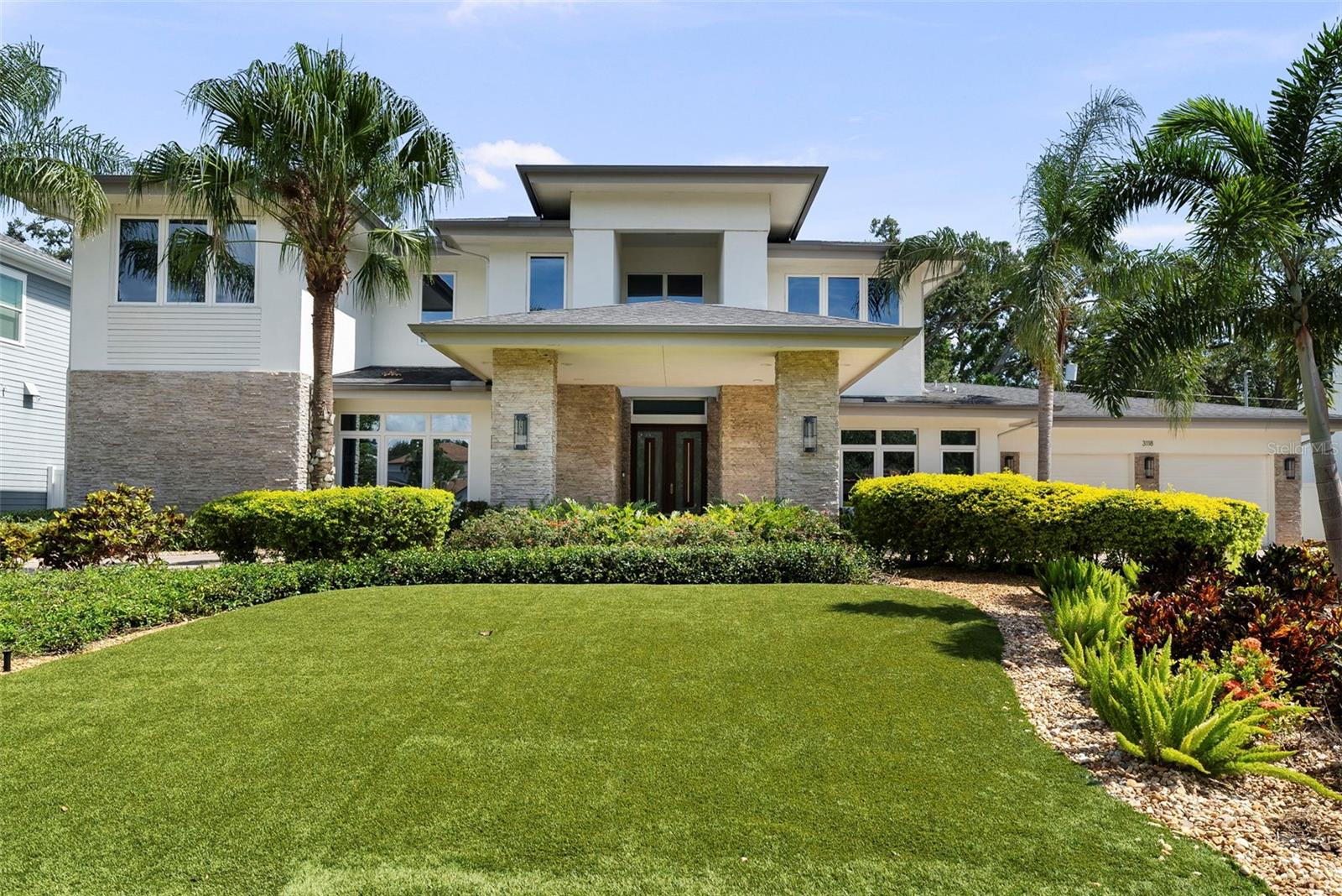 As you approach this stunning custom residence by Taralon Homes, a stately porte-cochère and circular brick driveway create a grand first impression, setting the stage for the refined elegance that lies within. Situated on a large, elevated lot with an expansive front lawn featuring manicured artificial turf and lush, tropical landscaping, the home enjoys a commanding presence just moments from Bayshore Boulevard. This contemporary masterpiece offers over 4,700 square feet of thoughtfully designed living space that seamlessly blends modern sophistication with everyday comfort.
A rare luxury in South Tampa, the oversized 4-car garage offers ample room for guests, a car collection, or additional storage needs.
Inside, every detail reflects quality and intention—from elegant custom lighting and designer fixtures to a floorplan that balances luxurious living with practical functionality. The home features five spacious bedrooms, three and a half bathrooms, a private study, an entertainment loft, a flexible multi-purpose room perfect for a gym, nursery, or second office, and generous storage throughout. Gently lived in, the home remains in pristine, like-new condition.
At the heart of the home is the spectacular chef’s kitchen, outfitted with sleek European-style cabinetry, quartz countertops, and high-end JennAir gas appliances. Three oversized islands serve distinct purposes—preparation, serving, and socializing—making this space ideal for entertaining and everyday living. Soaring ceilings with designer custom detailing and recessed lighting enhance the expansive open-concept layout.
Indoor-outdoor living is elevated by a dramatic 90-degree sliding glass wall that opens to a breathtaking two-story screened lanai. This private outdoor retreat features a gas-heated spa, dual-sided fireplace, built-in gas firepit, and a fully equipped outdoor kitchen, all set among travertine pavers, manicured artificial turf, and full privacy fencing.
Modern technology and peace of mind are seamlessly integrated throughout the home. A whole-house Control4 system manages smart home functions, including the thermostat control, with all equipment discreetly housed in its own dedicated room. Additional features include a security system with cameras and a whole-house natural gas generator for enhanced safety and convenience.
Located in Flood Zone X—no flood insurance required.
This is more than a home—it’s a curated lifestyle in one of South Tampa’s most desirable neighborhoods.