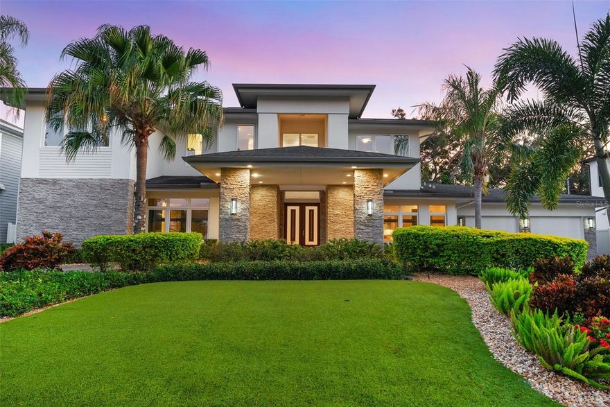 Just moments from Bayshore Boulevard and located in coveted Flood Zone X (no flood insurance required), this custom Taralon Homes masterpiece offers a rare combination of luxury and practicality with a 4-car garage, porte-cochère, and first-floor primary suite. A stately circular brick driveway and grand porte-cochère create an impressive entrance, leading to more than 4,700 sq ft of modern sophistication and thoughtful design. Set on an elevated lot with manicured artificial turf and lush tropical landscaping, the home blends timeless curb appeal with low-maintenance living.

Inside, soaring ceilings, elegant lighting, and refined finishes create an atmosphere of understated elegance. The spectacular chef’s kitchen showcases sleek European-style cabinetry, quartz countertops, premium JennAir gas appliances, and three oversized islands designed for cooking, serving, and gathering. Pocketed sliding doors open the expansive great room to a beautifully designed screened lanai featuring a heated plunge pool with spa, dual-sided fireplace, built-in firepit, and outdoor kitchen surrounded by travertine pavers, manicured turf, and full privacy fencing—an entertainer’s dream.

The primary suite, private study, and flex room (ideal for a gym, nursery, or second office) are conveniently located on the main level, while upstairs you’ll find four additional bedrooms and a spacious entertainment loft. Smart-home technology includes a whole-house Control4 system, security cameras, and a natural-gas generator for peace of mind. Meticulously maintained, this home delivers the perfect blend of luxury, comfort, and convenience in one of South Tampa’s most desirable neighborhoods.